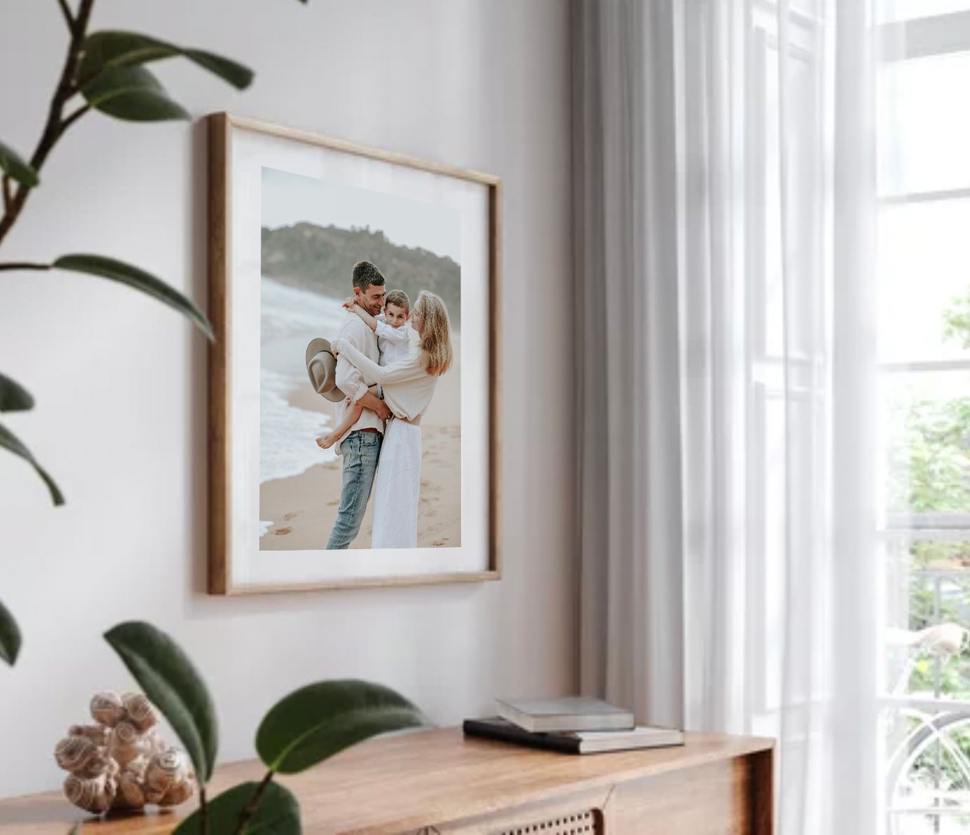 Framed beach couple photo in wooden frame displayed on white wall above dresser in bright modern living room.