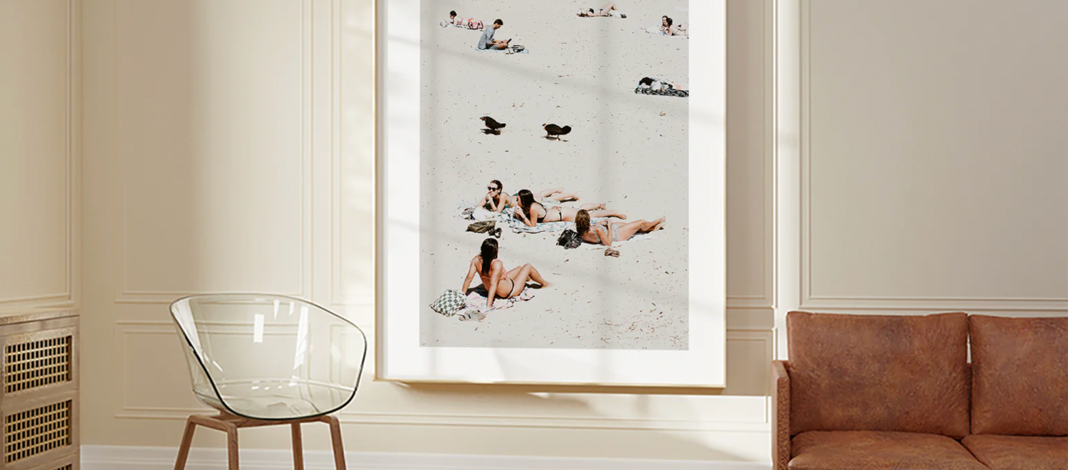 Framed beach art print displayed on wall above leather sofa.