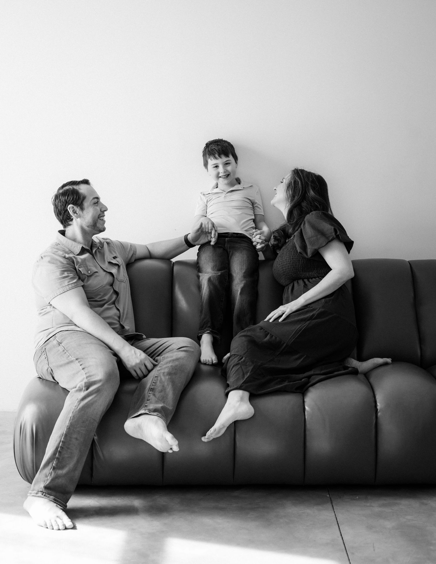 A sequence of black and white photos showing playful interactions between two people lounging on a couch.