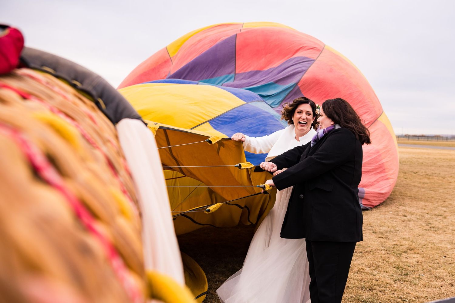 Hot air balloon being prepared for flight in empty field during colorful sunrise wedding.