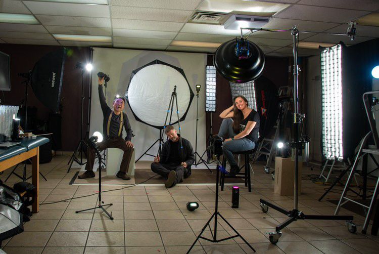 Professional photography studio setup with multiple lights, reflectors, and equipment arranged for a photo session.