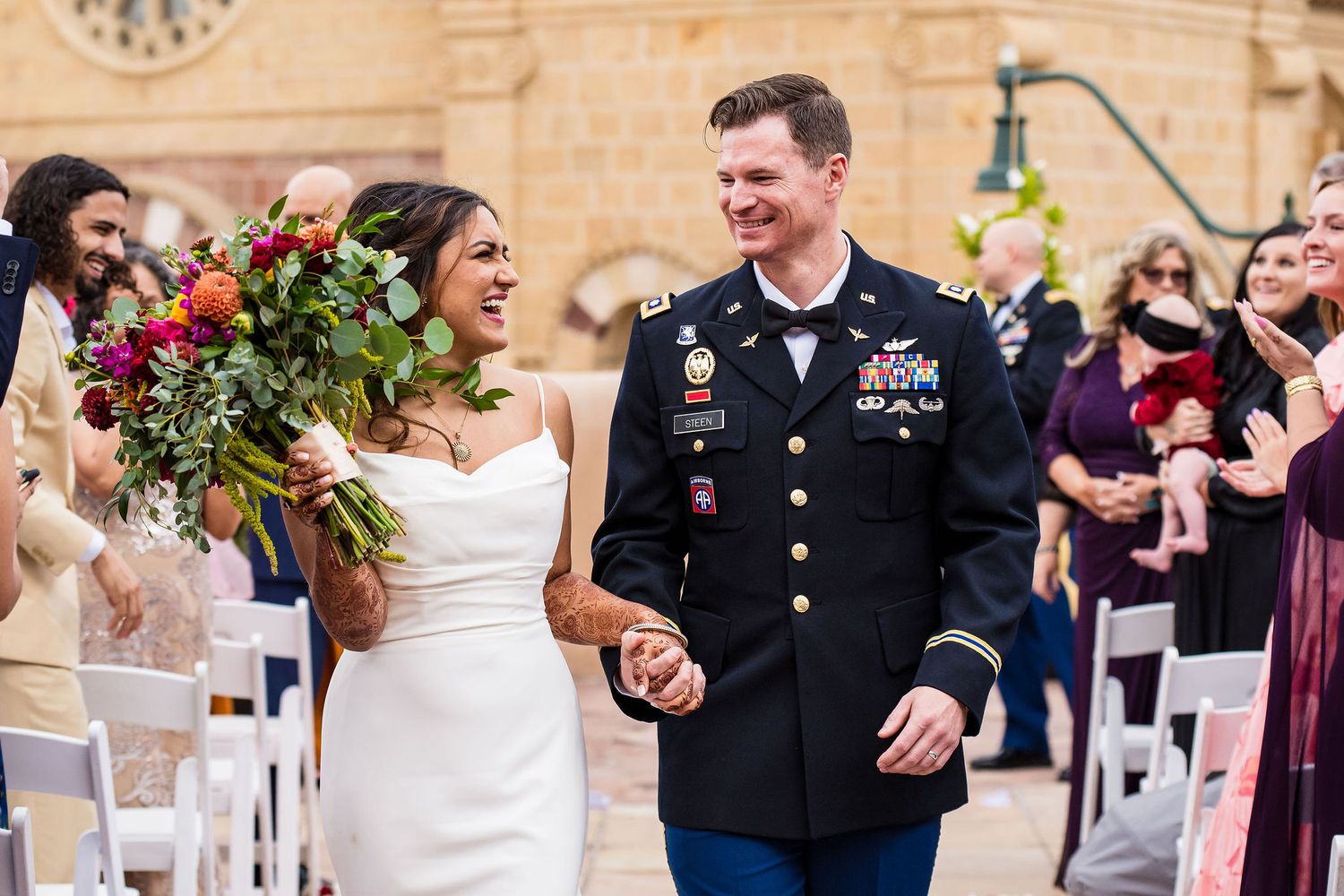 Newlyweds walking down aisle with joyful expressions at outdoor wedding ceremony at La Fonda on the Plaza in Santa Fe, New Mexico.