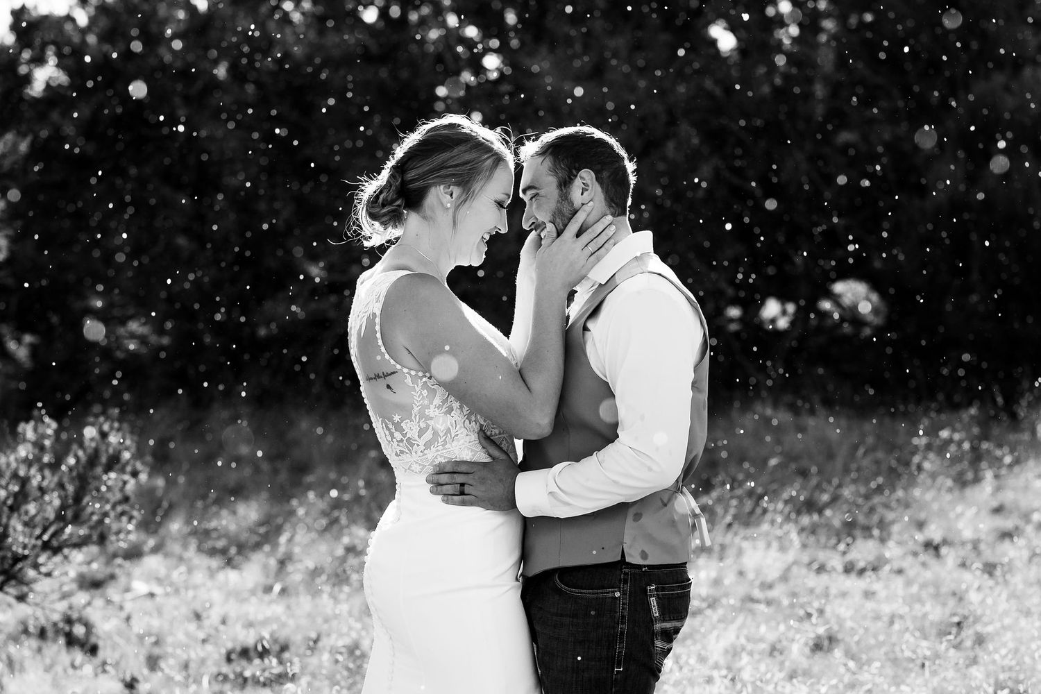 Black and white romantic photograph of a couple embracing outdoors during their wedding day while the rain falls in Quemado, New Mexico.