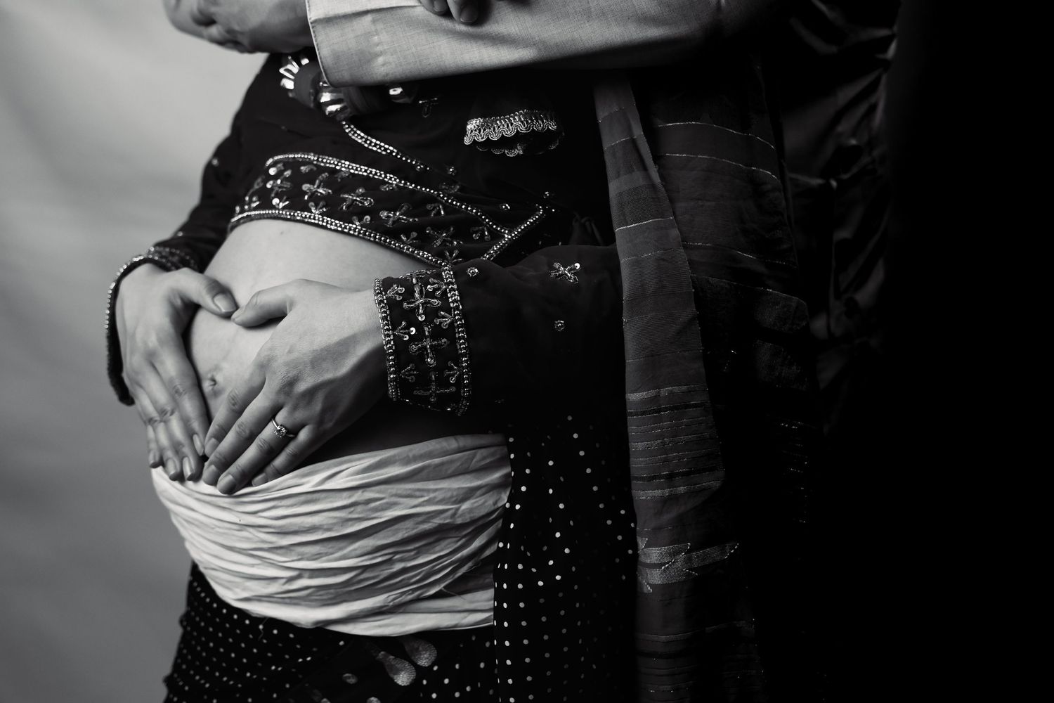 Artistic maternity photos capturing loving moments in dramatic black and white lighting.