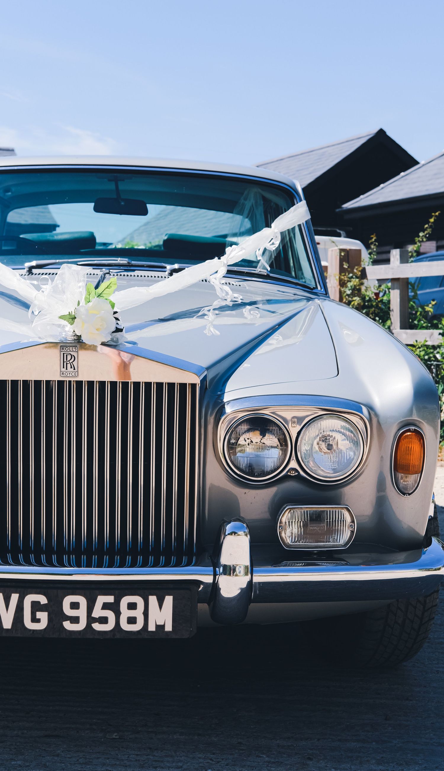 Close-up of a silver Rolls Royce front grille and headlights with registration plate VG 958M.
