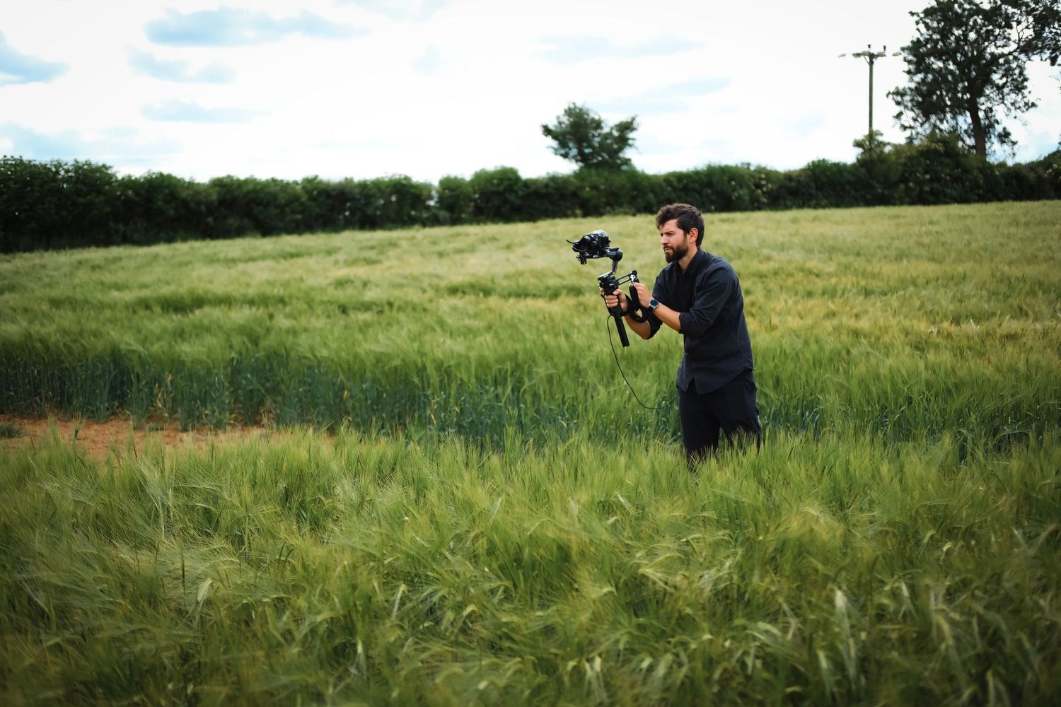 Photographer working with camera equipment in green summer field.