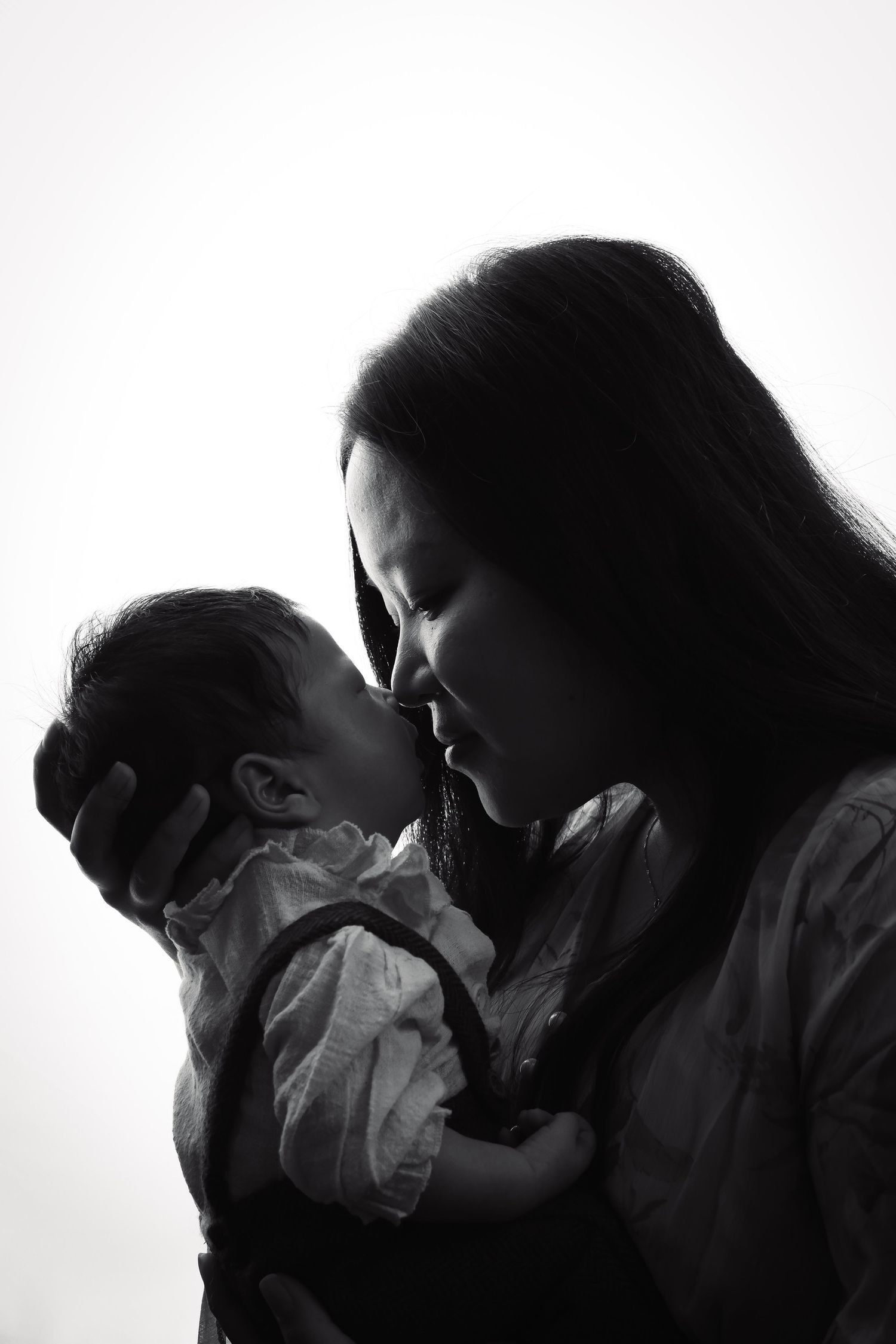 Silhouette family portrait showing tender interaction against white backdrop.