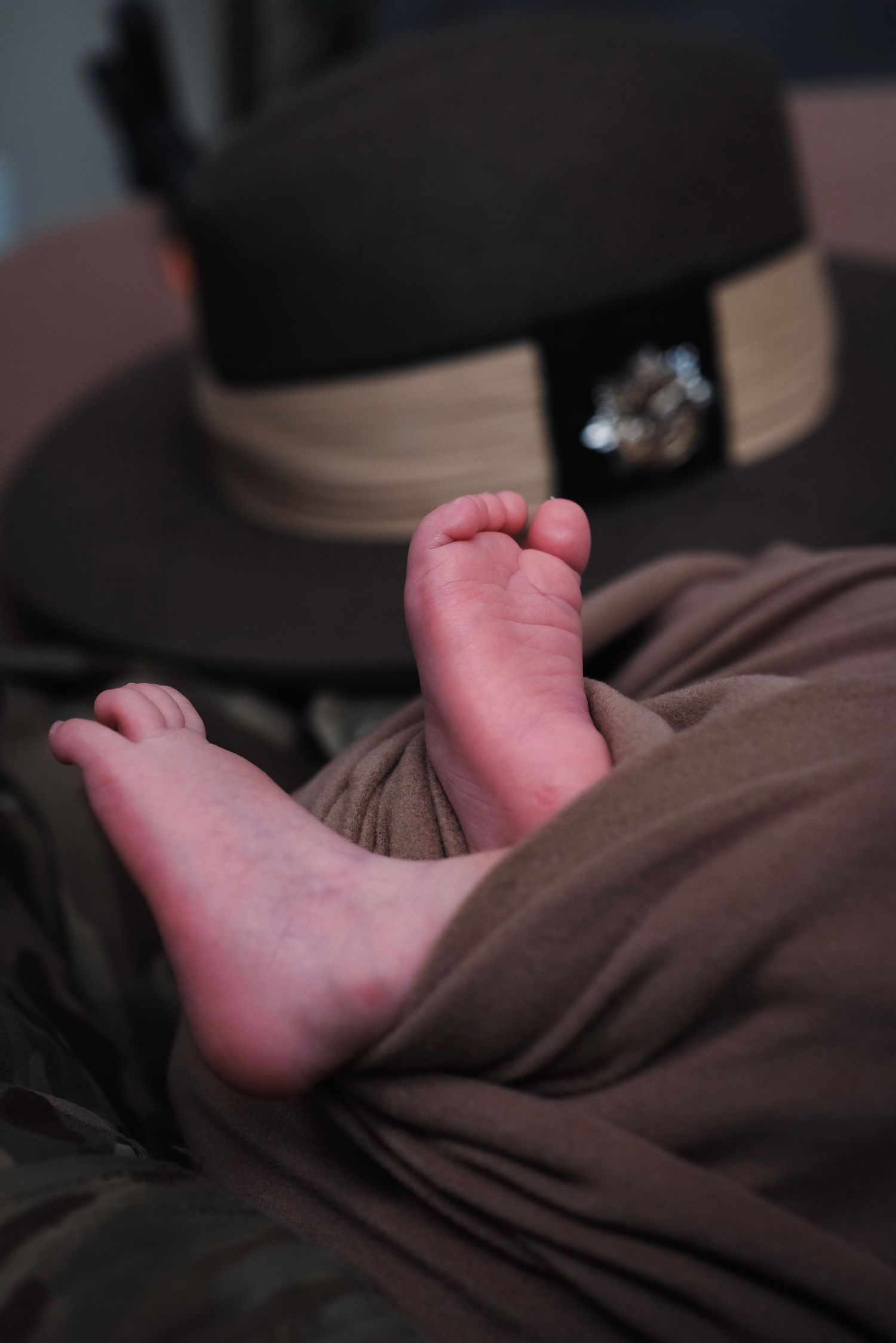 Close-up series of baby feet wrapped in brown fabric against dark background.