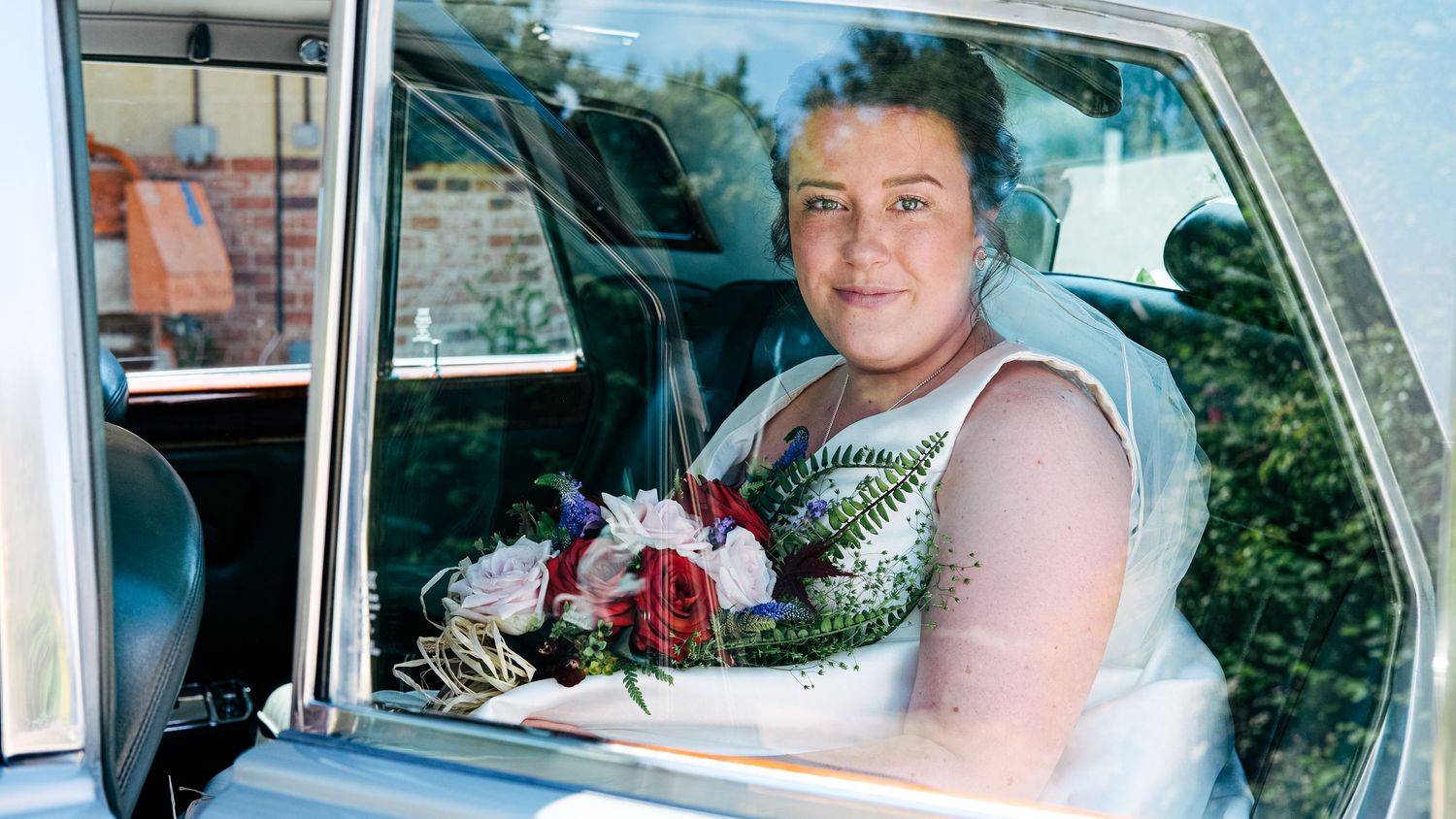 Interior view of a classic car with white leather seats and dashboard visible through windshield.