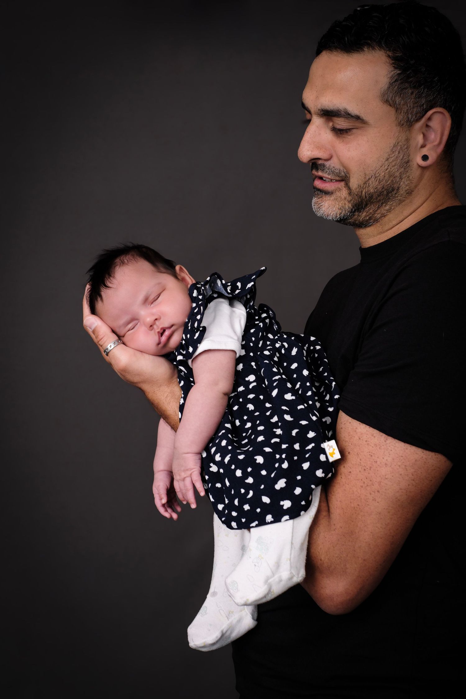 Baby in polka dot outfit sleeping peacefully while being cradled.