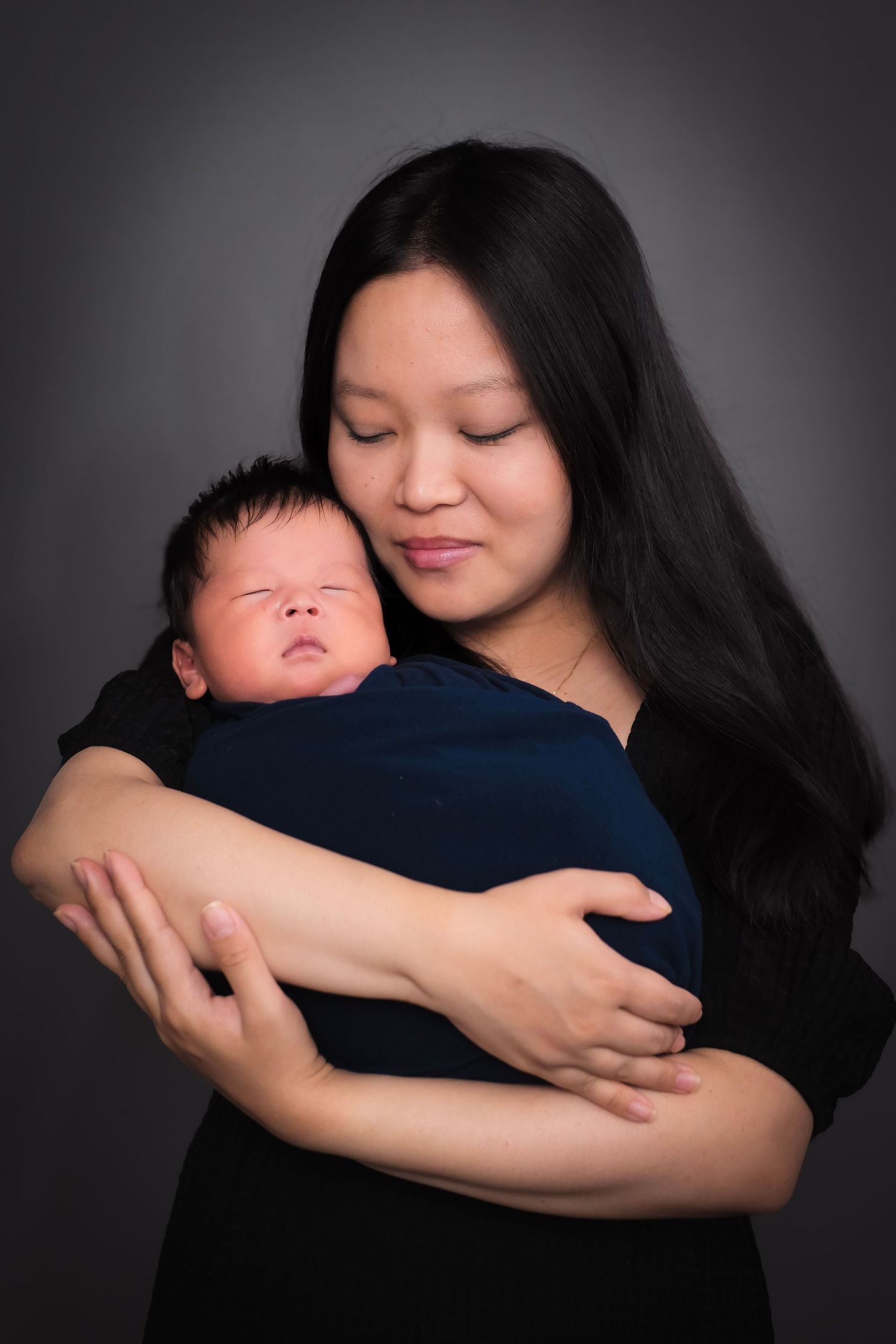 Tender moments between parent and sleeping infant in studio setting.