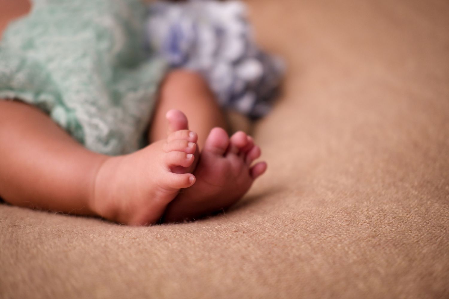 Close-up detail of tiny baby feet against soft textured background.