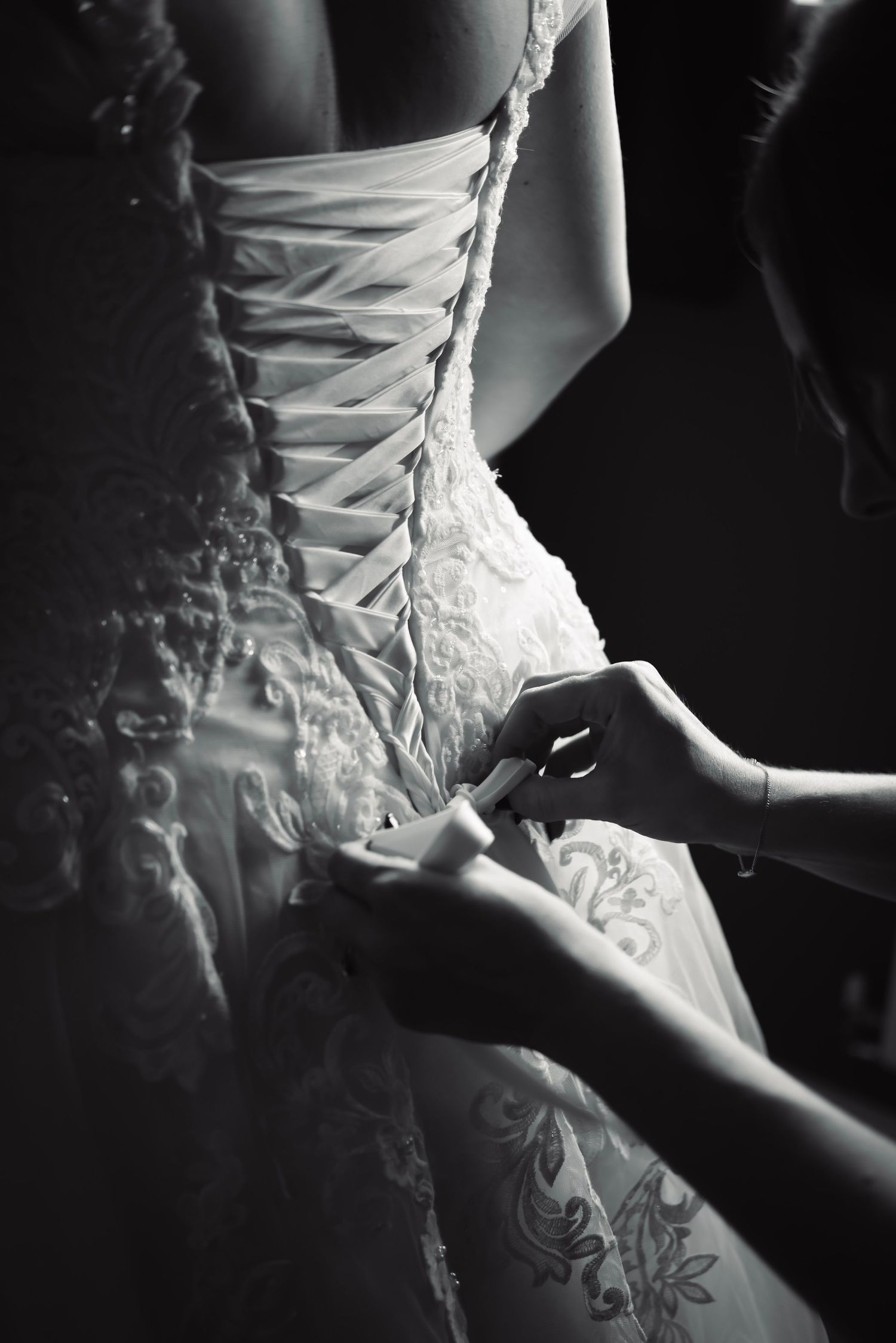 Close-up of intricate corset lacing on white wedding dress.