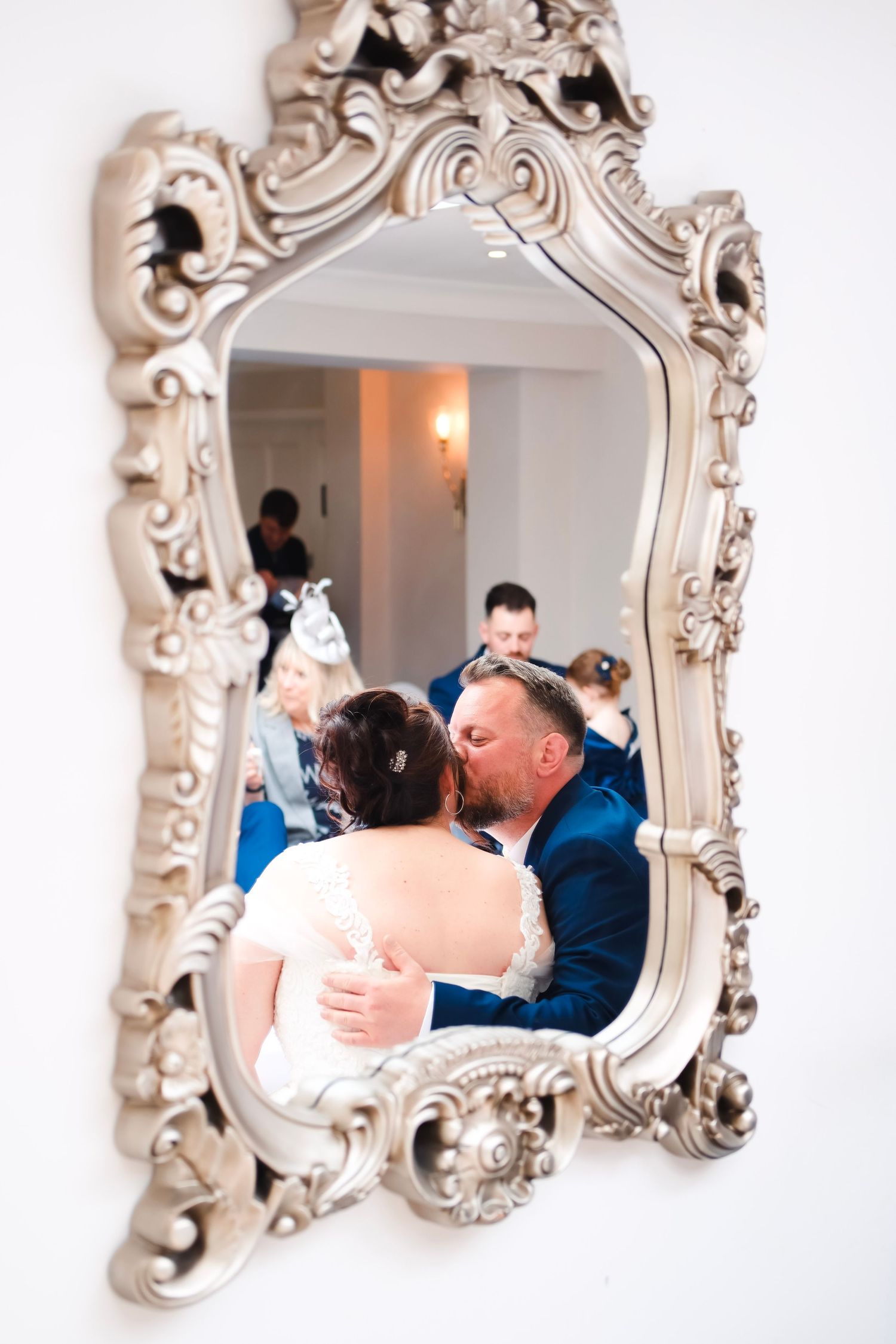 Ornate vintage mirror reflects intimate wedding moment in elegant frame.