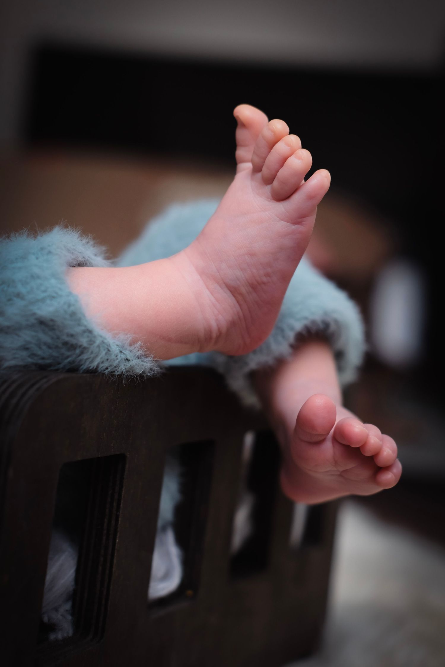 Artistic detail shot of baby feet against dark background.