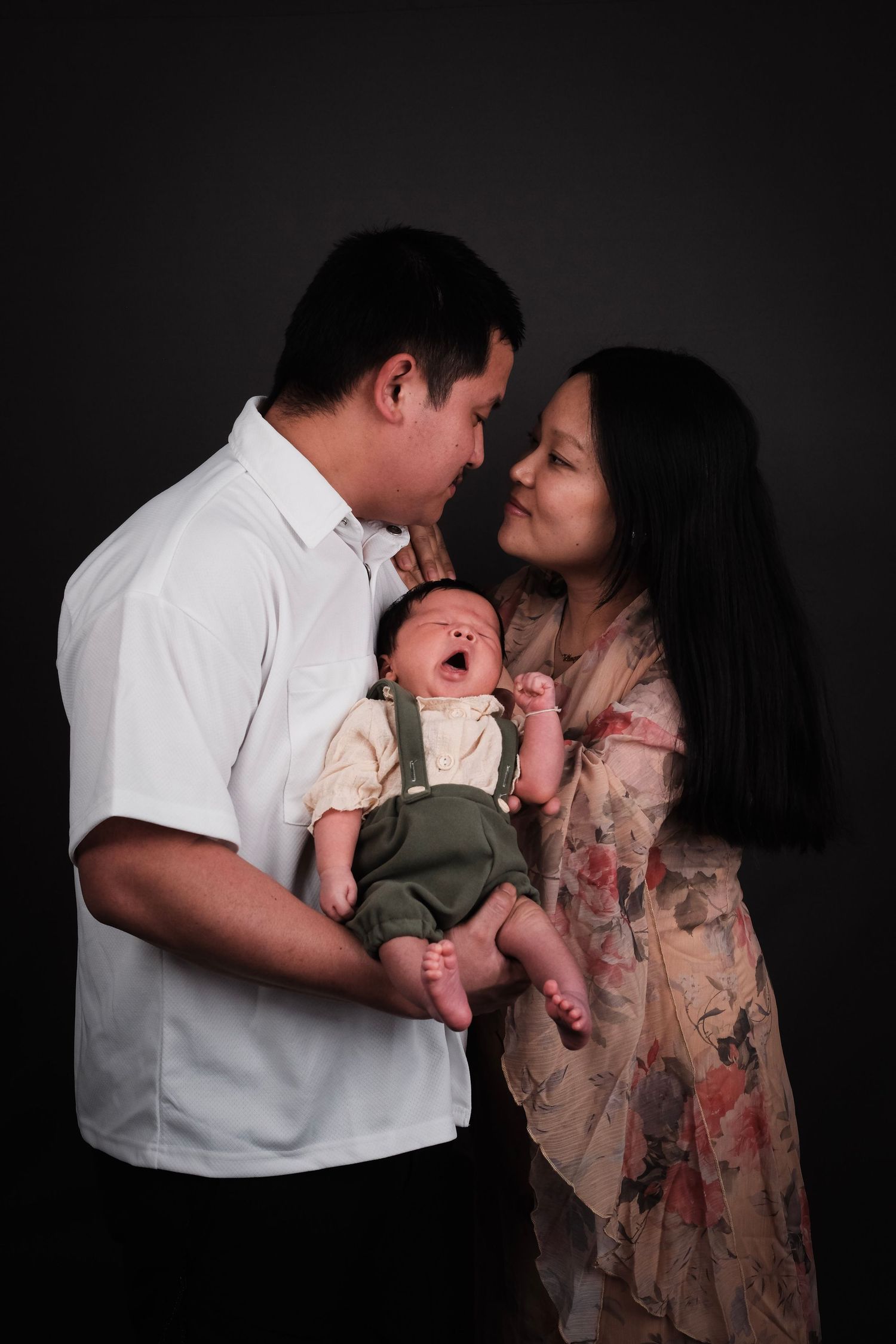 Intimate family portrait with soft lighting against dark background.