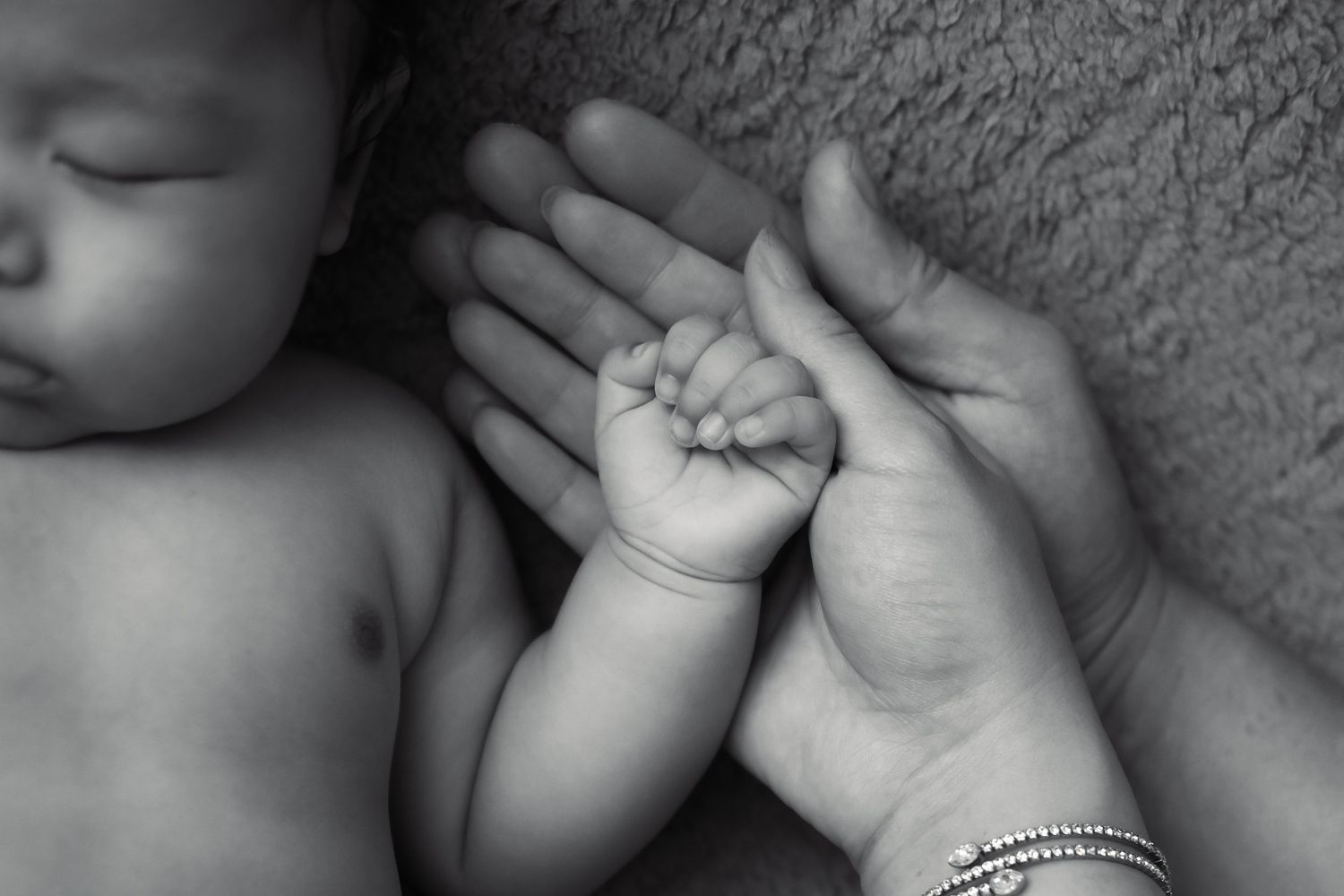 Artistic black and white close-up of baby's tiny hands and fingers.