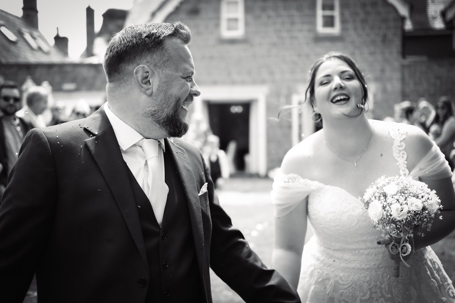 Black and white portrait captures candid laughter during wedding celebration.