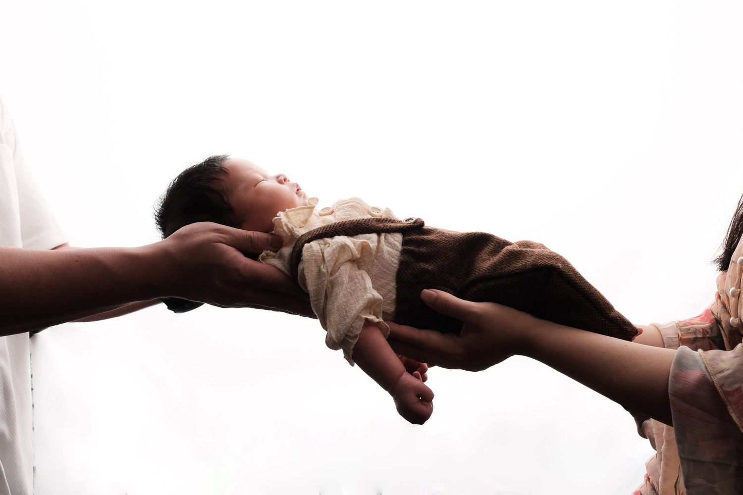 Newborn photography session showing tiny feet and hands against dark background.