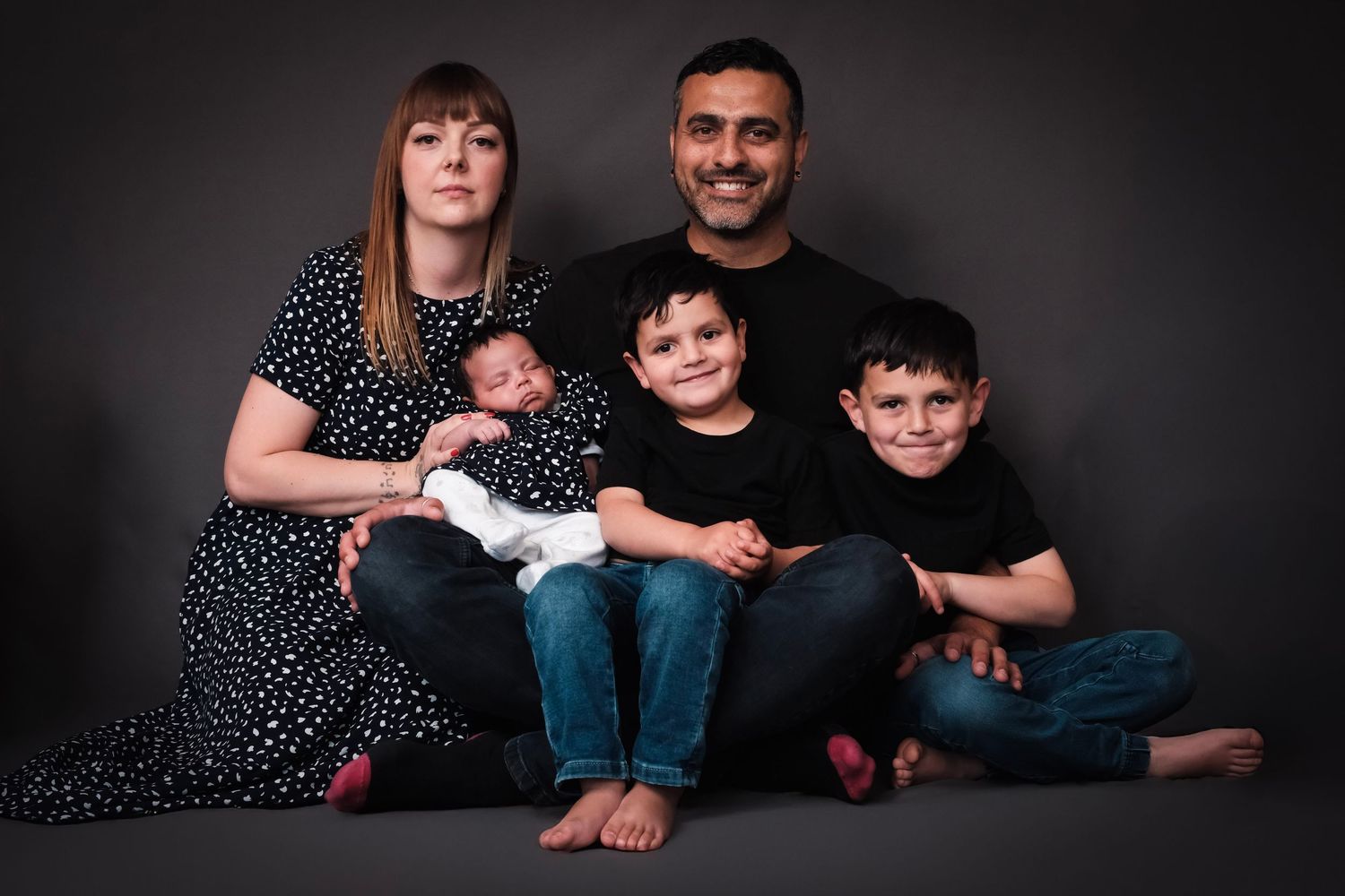 Family portrait session against dark background showing loving connection.