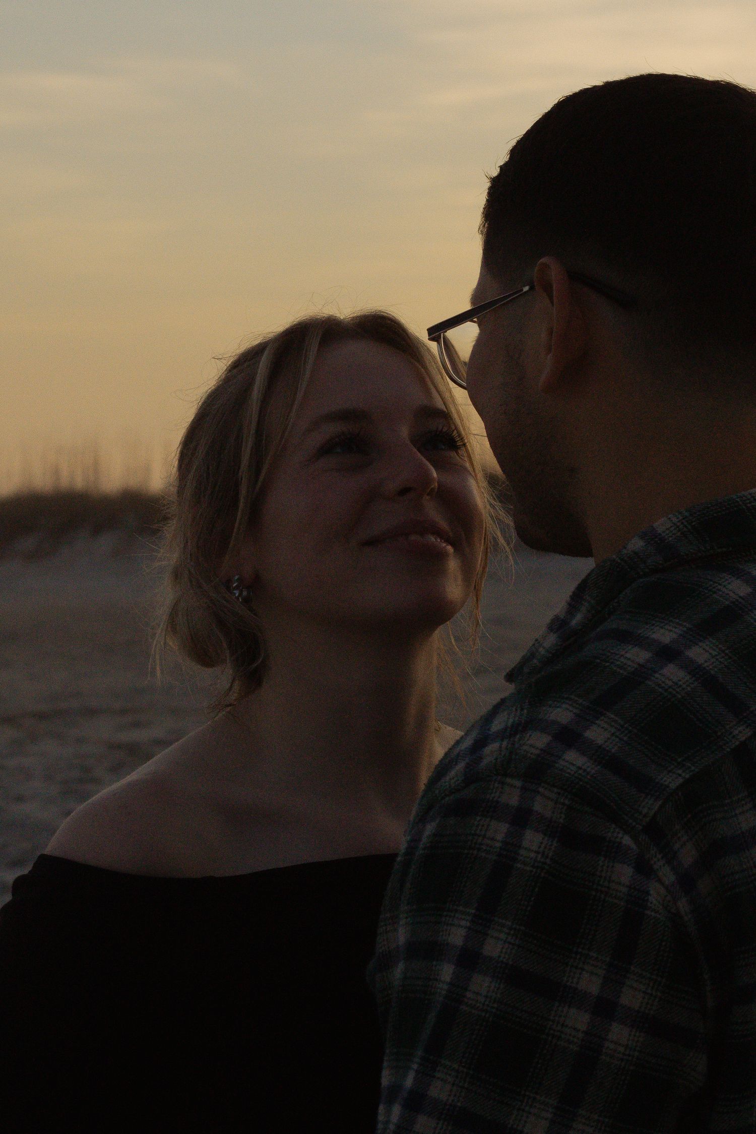 Couple looking into each others eyes at sunset along the shoreline during their Wrightsville Beach engagement photography session.