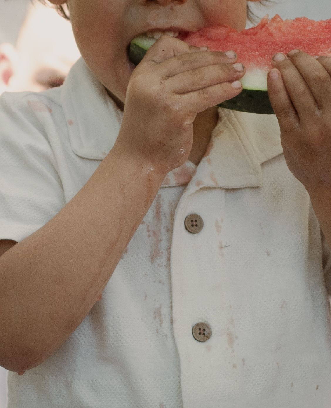 Child eating a slice of watermelon during a candid family photography session in Raeford, NC.