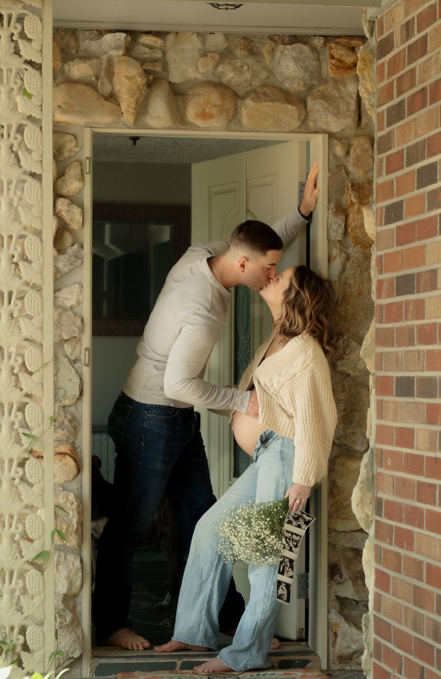 Expecting couple kissing in doorway during a candid maternity photography session in Fayetteville, NC.