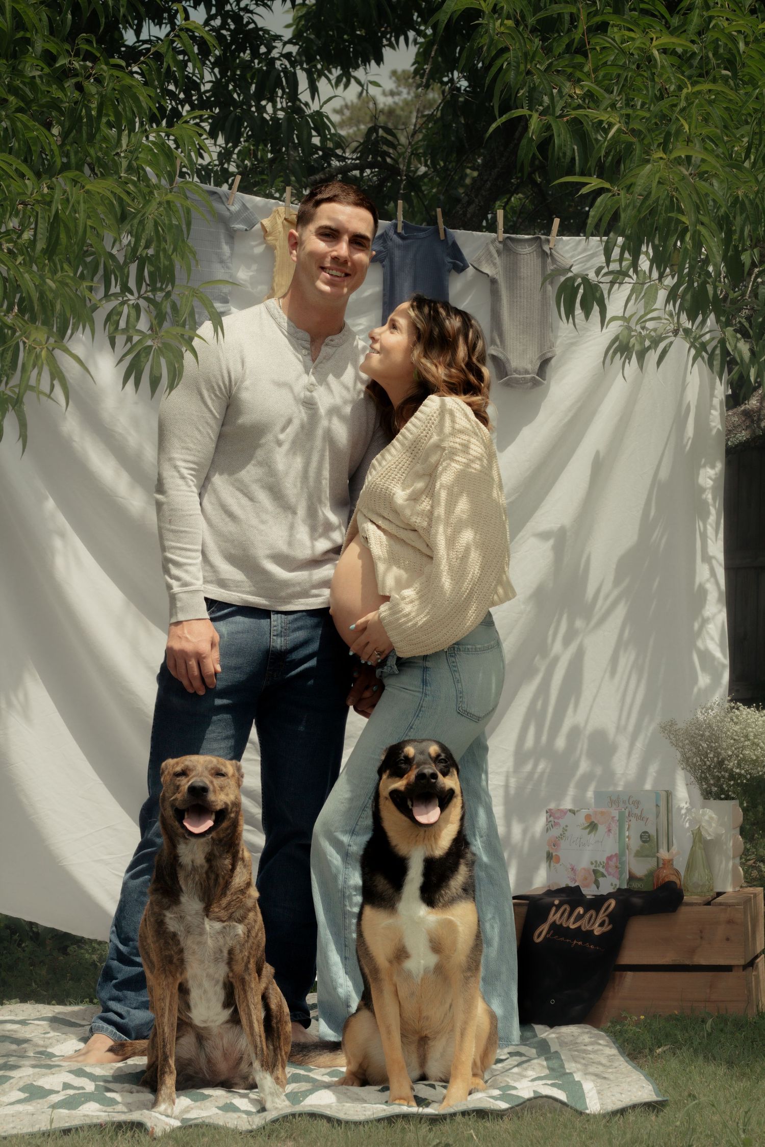 Expecting couple smiling with their two dogs during a candid maternity photography session in Fayetteville, NC.