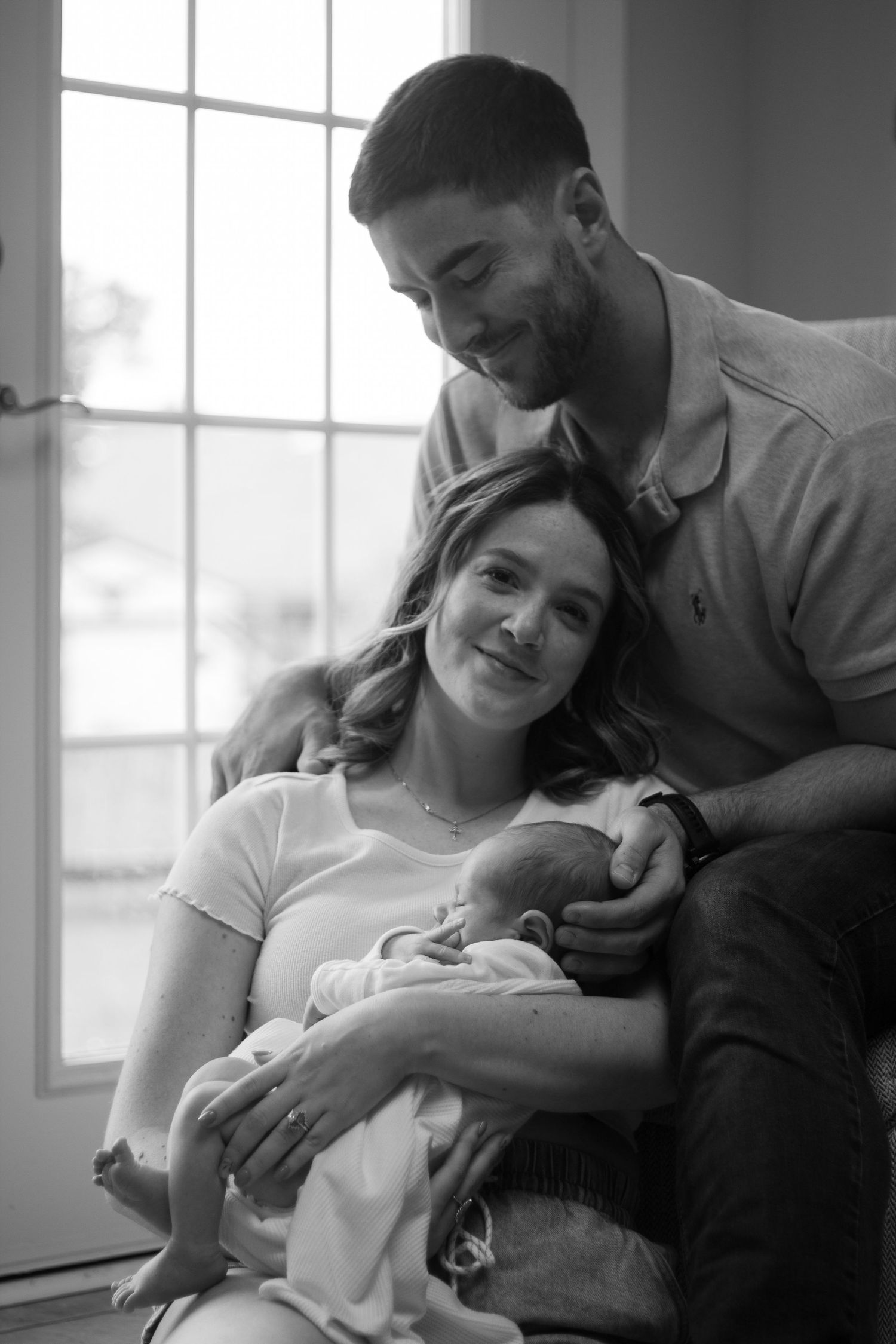 Parents cuddling their newborn baby during an intimate newborn photography session in Fayetteville, NC.