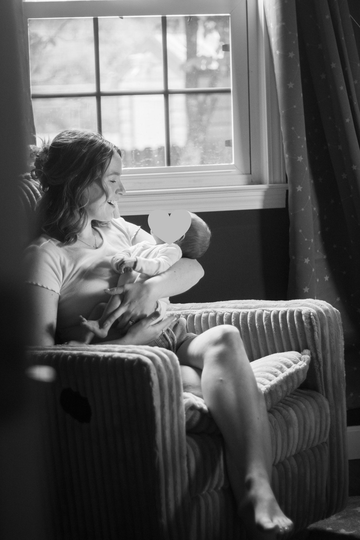 Mother holding newborn baby in arms in rocking chair in nursery during a newborn photography session in Fayetteville, NC.