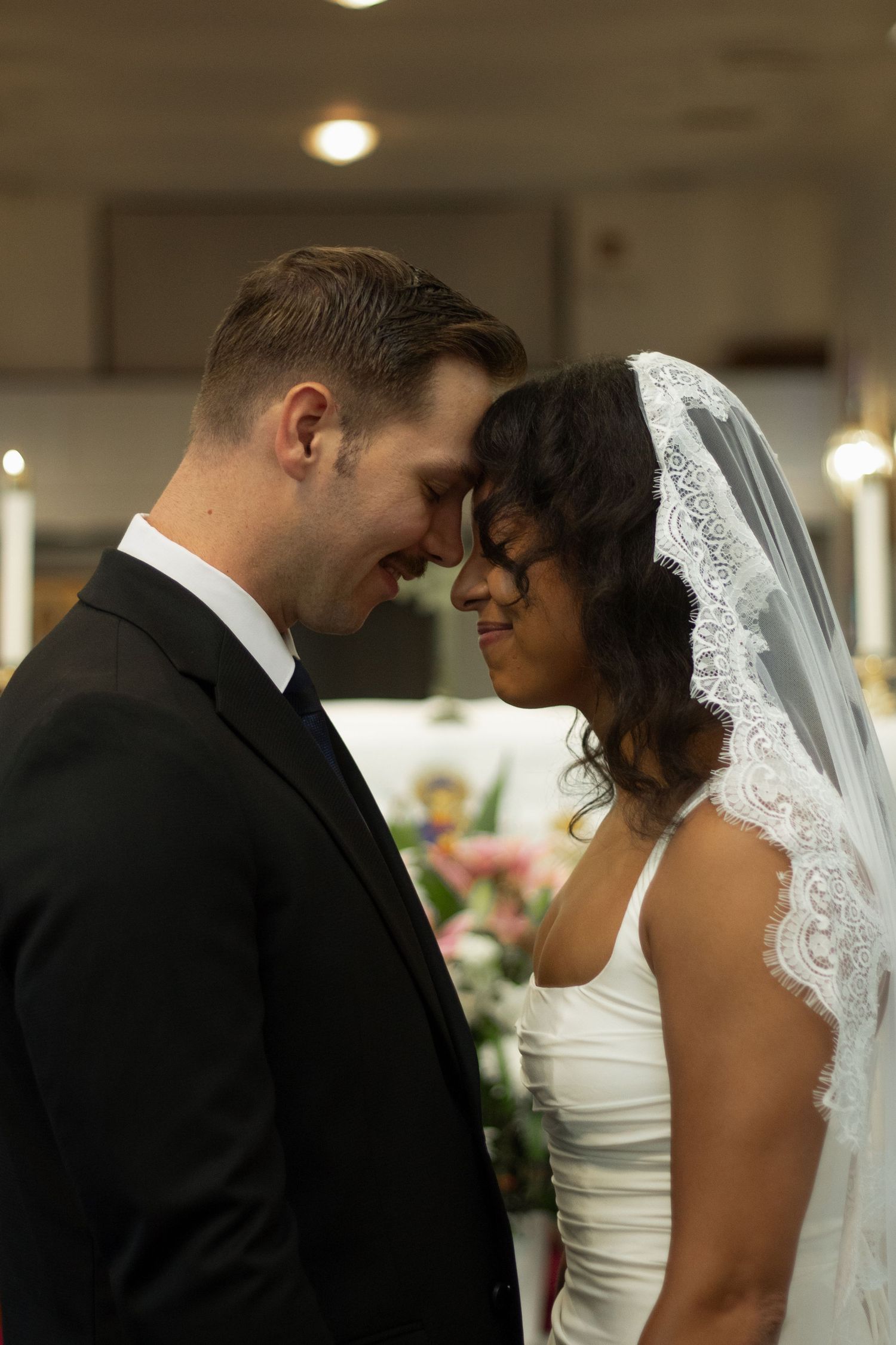 Bride and groom standing together foreheads touching  at the altar after their intimate church wedding in Fayetteville, NC.