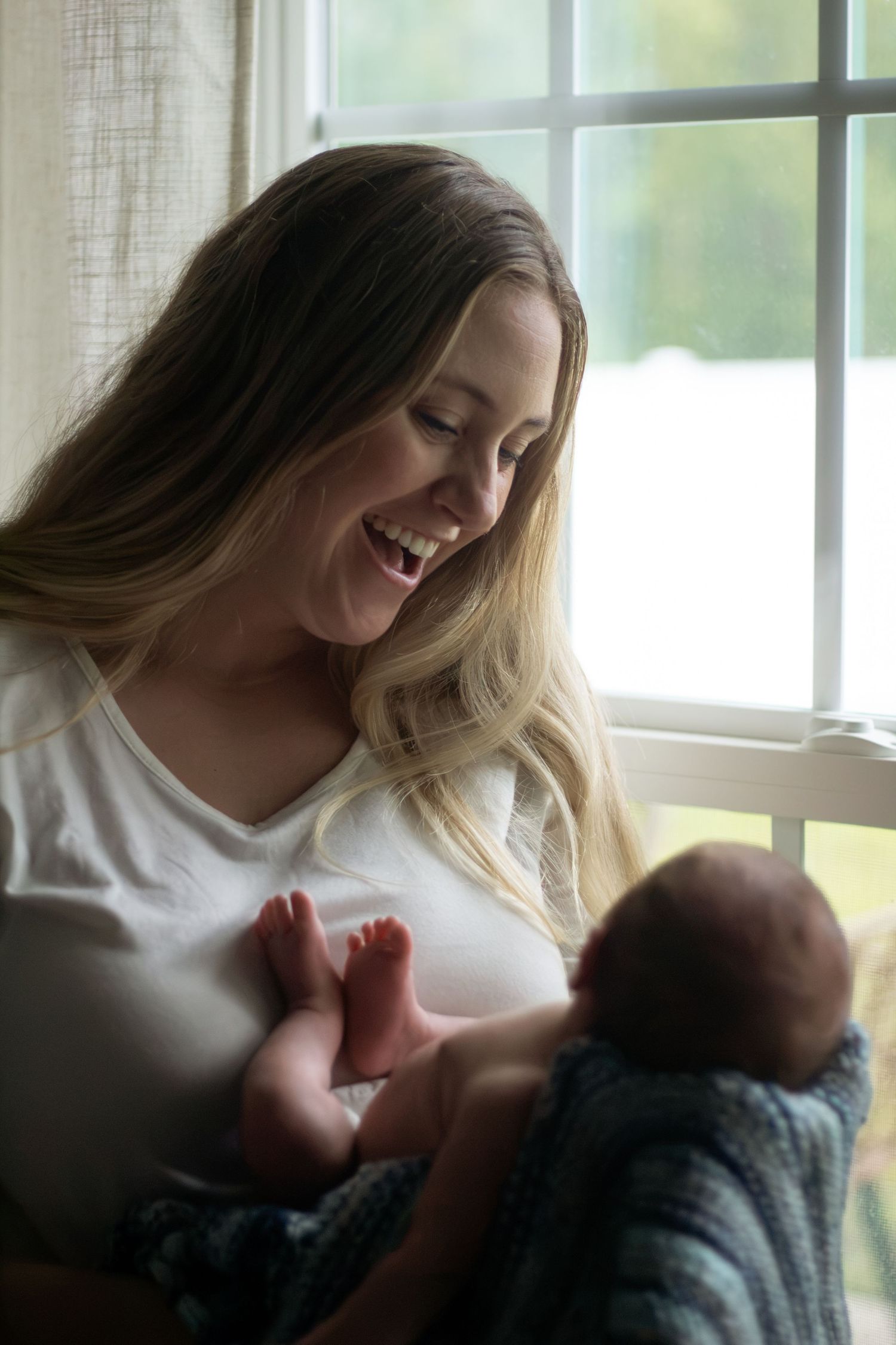 Mother holding newborn baby in arms during a newborn photography session in Fayetteville, NC.