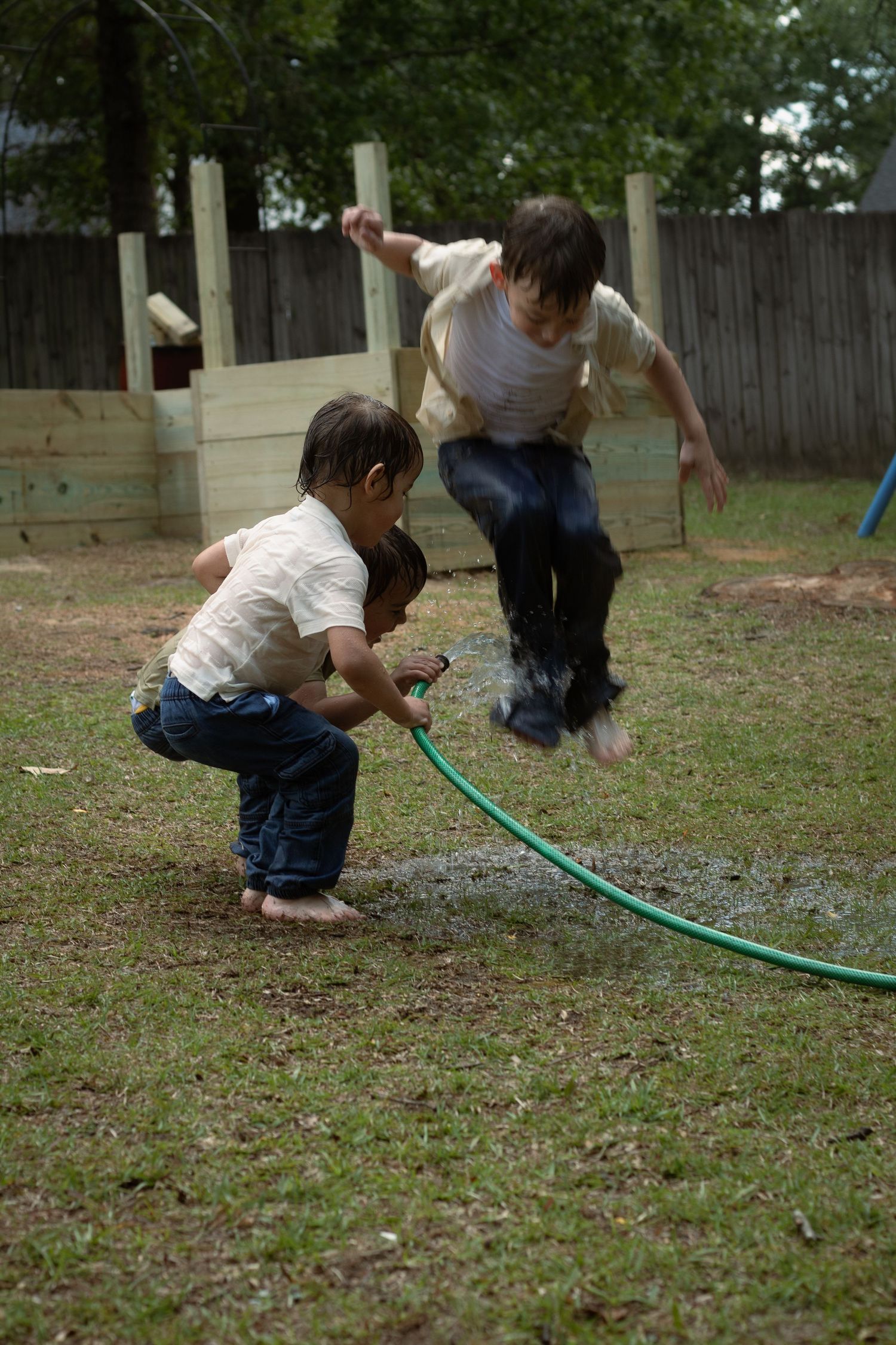 Children laughing as jump in puddle during a fun backyard family session in Raeford, NC.