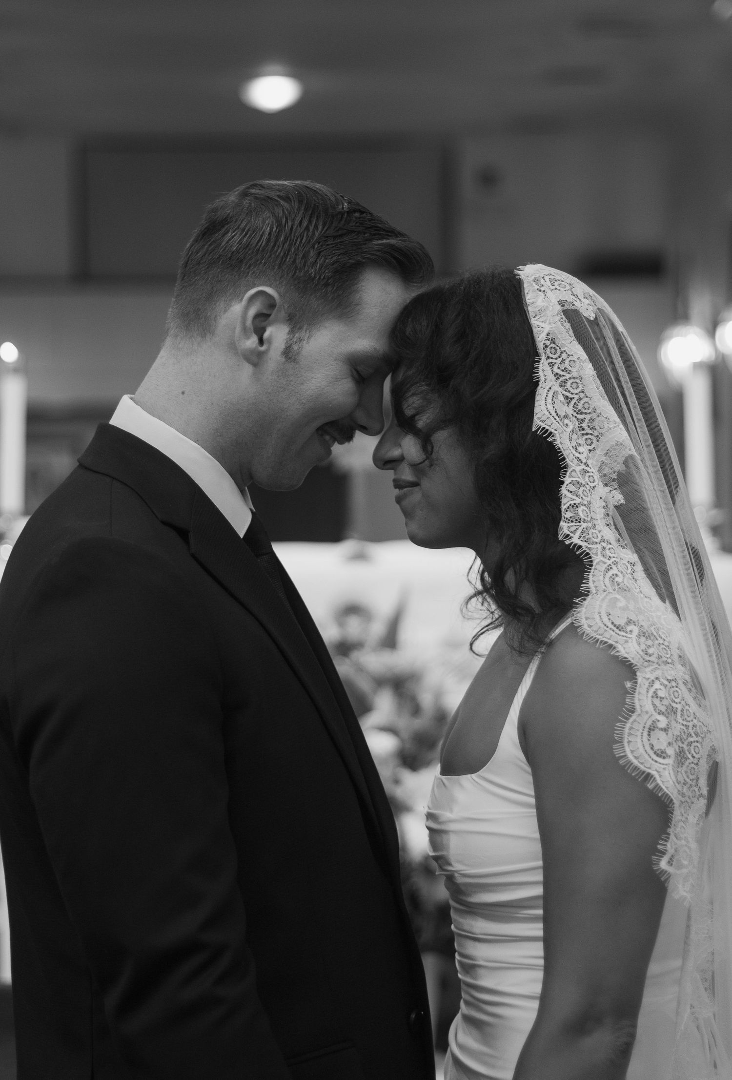 Bride and groom standing together foreheads touching  at the altar after their intimate church wedding in Fayetteville, NC; Black and white.