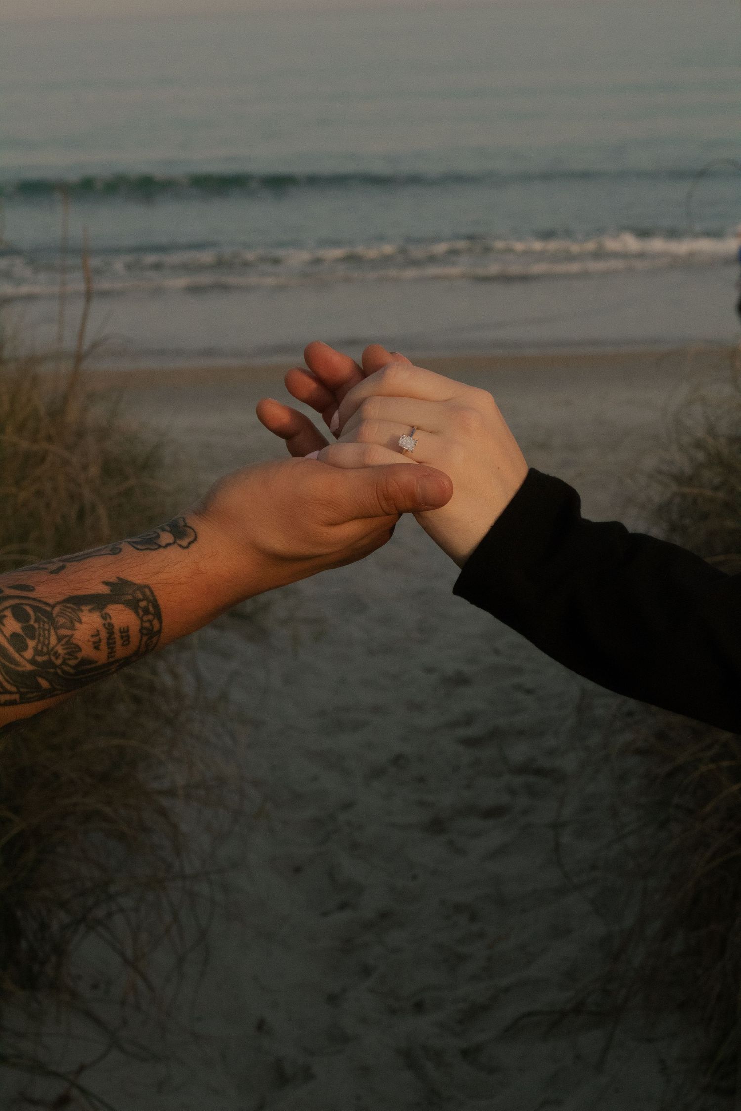 Close-up of the couple's engagement ring during their beach engagement photography session in Wrightsville Beach, NC.