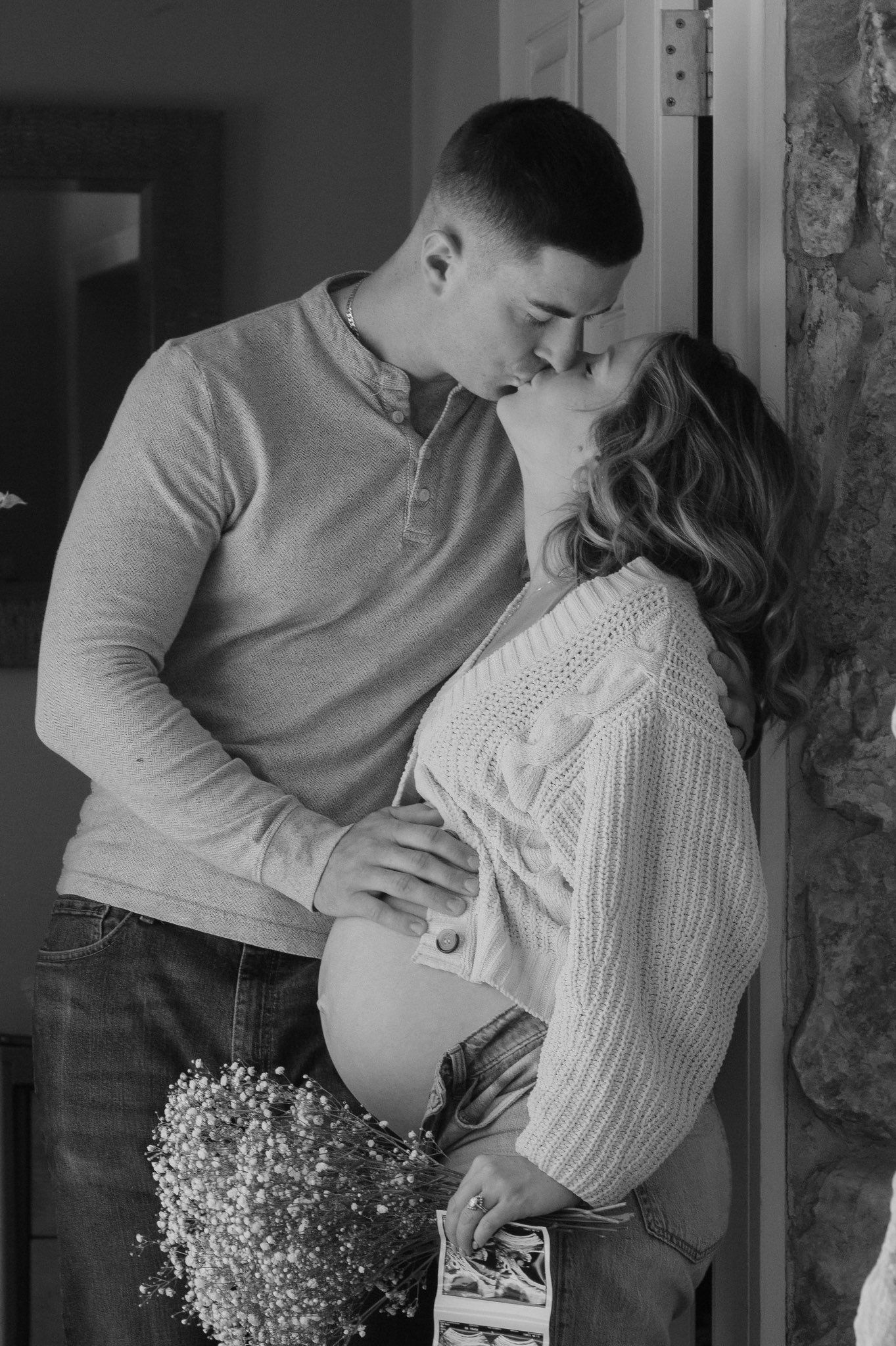 Expecting couple kissing in doorway during a candid maternity photography session in Fayetteville, NC.