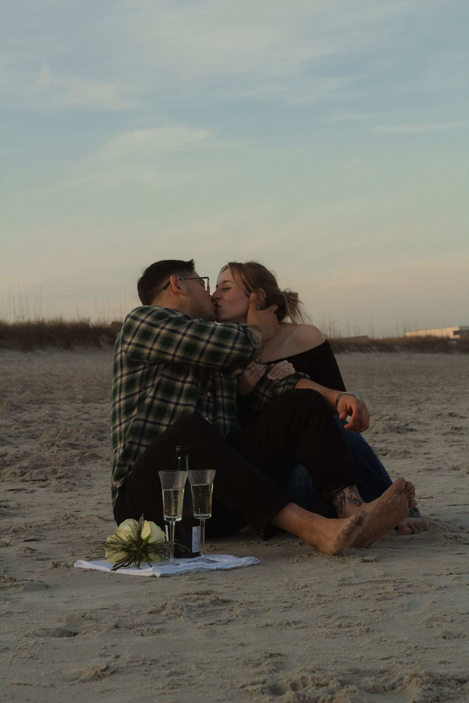 Engaged couple sharing a kiss by the ocean during a sunset engagement session in Wrightsville Beach, NC.