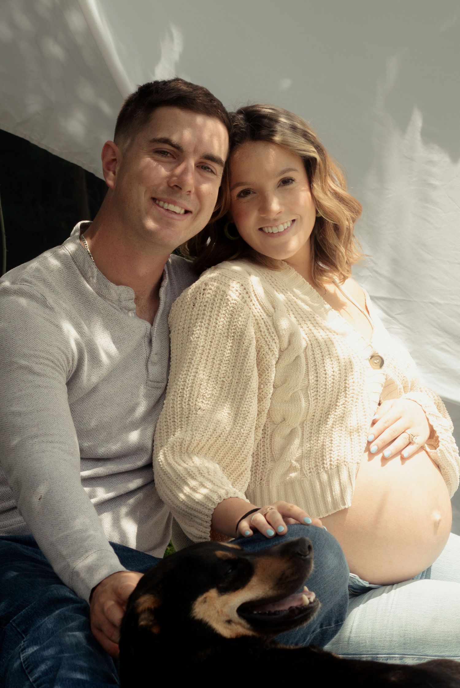 Expecting couple smiling during a candid maternity photography session in Fayetteville, NC.