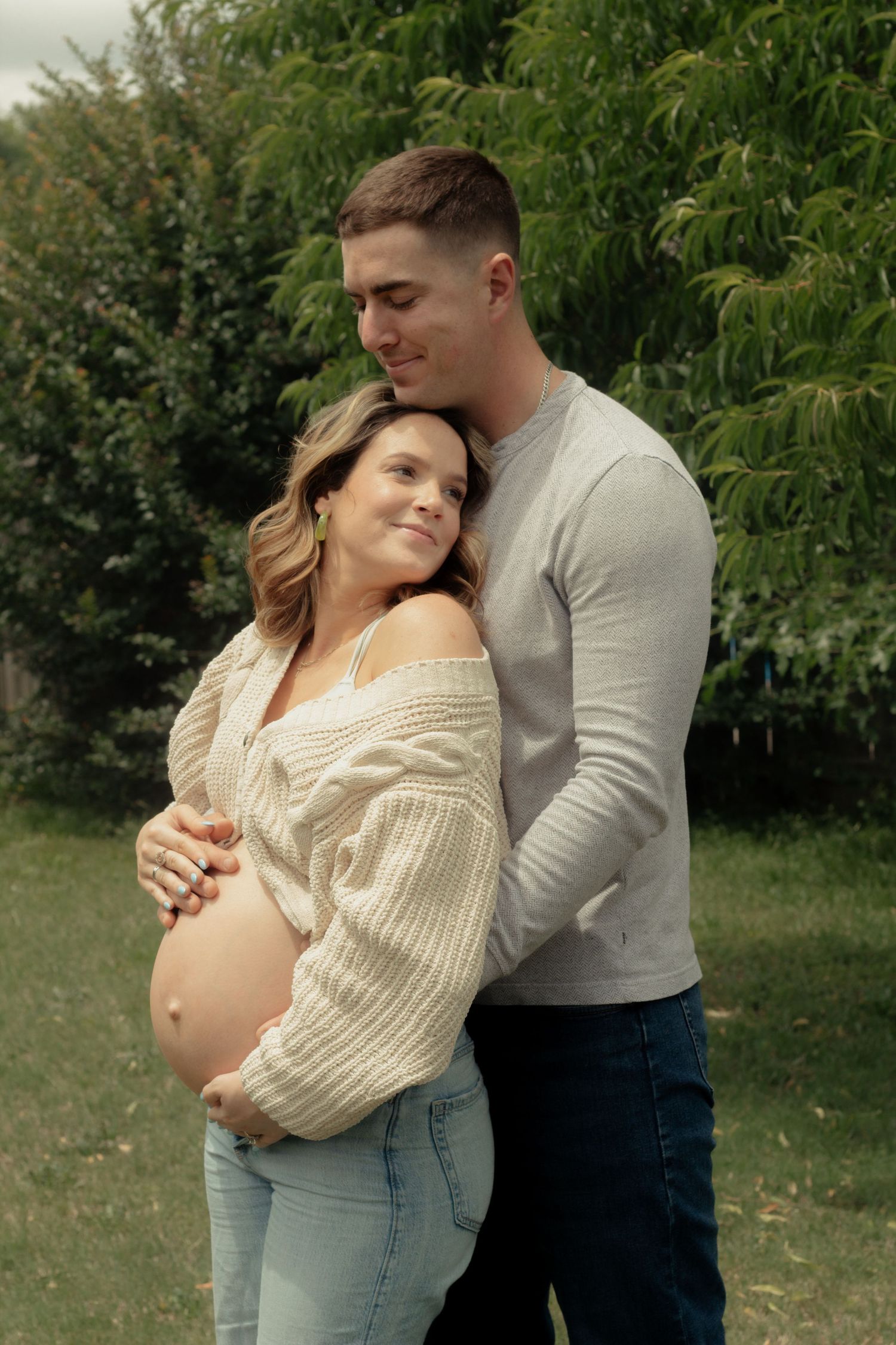 Expecting couple embracing during a candid maternity photography session in Fayetteville, NC.