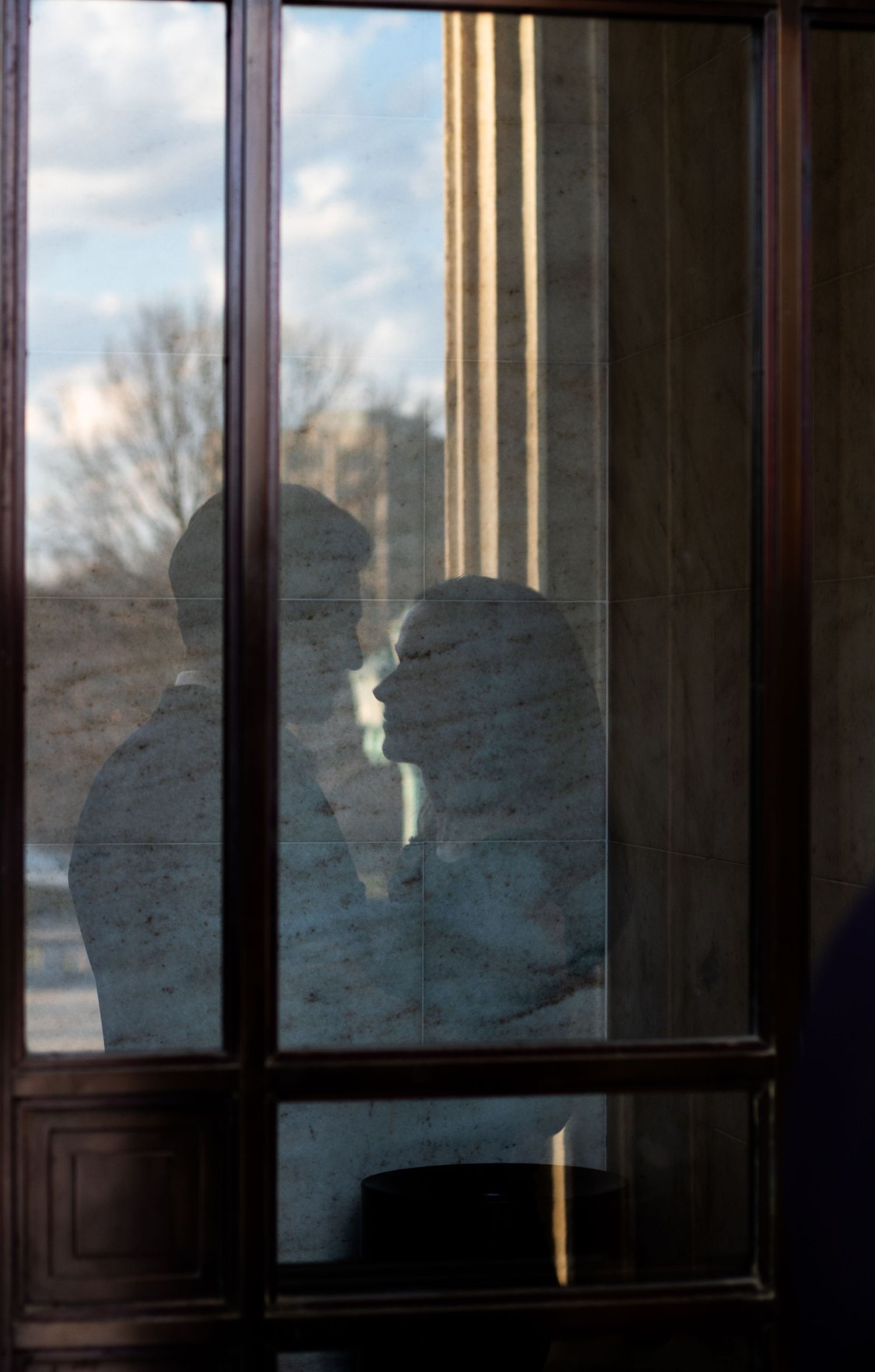 Photo of reflection in window of engaged couple sharing a quiet moment outside the Cleveland Museum of Art in Cleveland, Ohio.