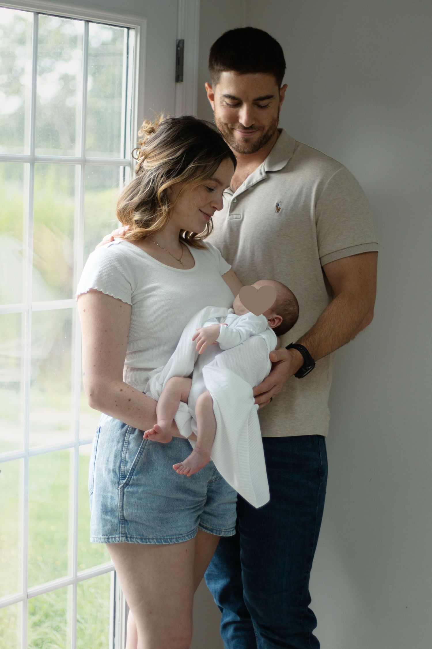 Parents cuddling their newborn baby during an intimate newborn photography session in Fayetteville, NC.