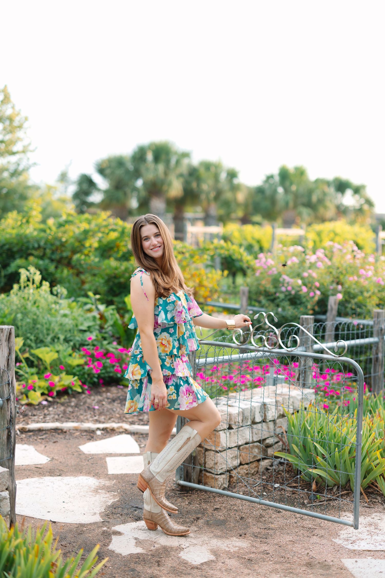 Summer garden portrait session featuring floral dress and decorative metal fence.