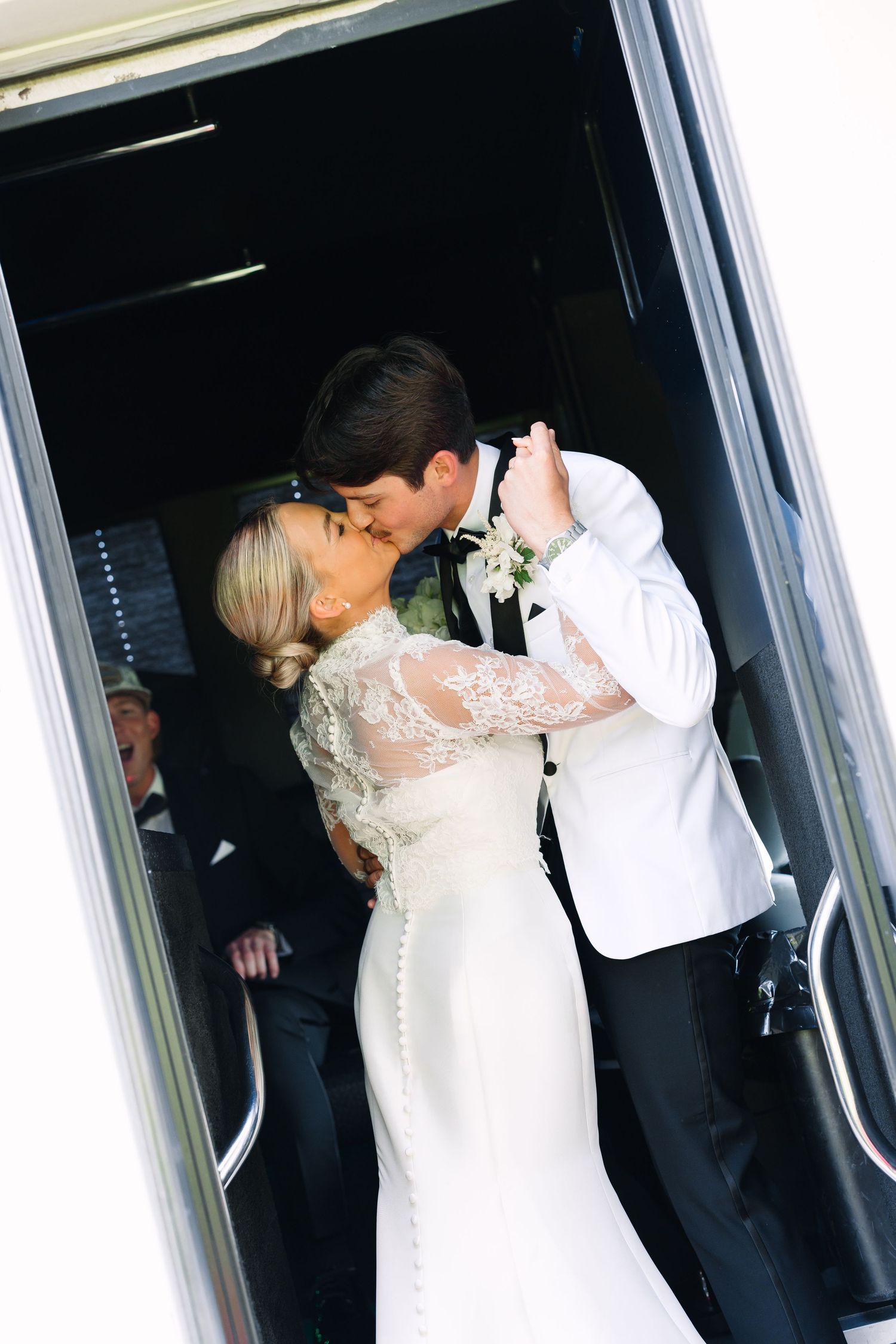 Bride and groom share a romantic kiss in a doorway, bride wearing lace long-sleeve wedding gown.