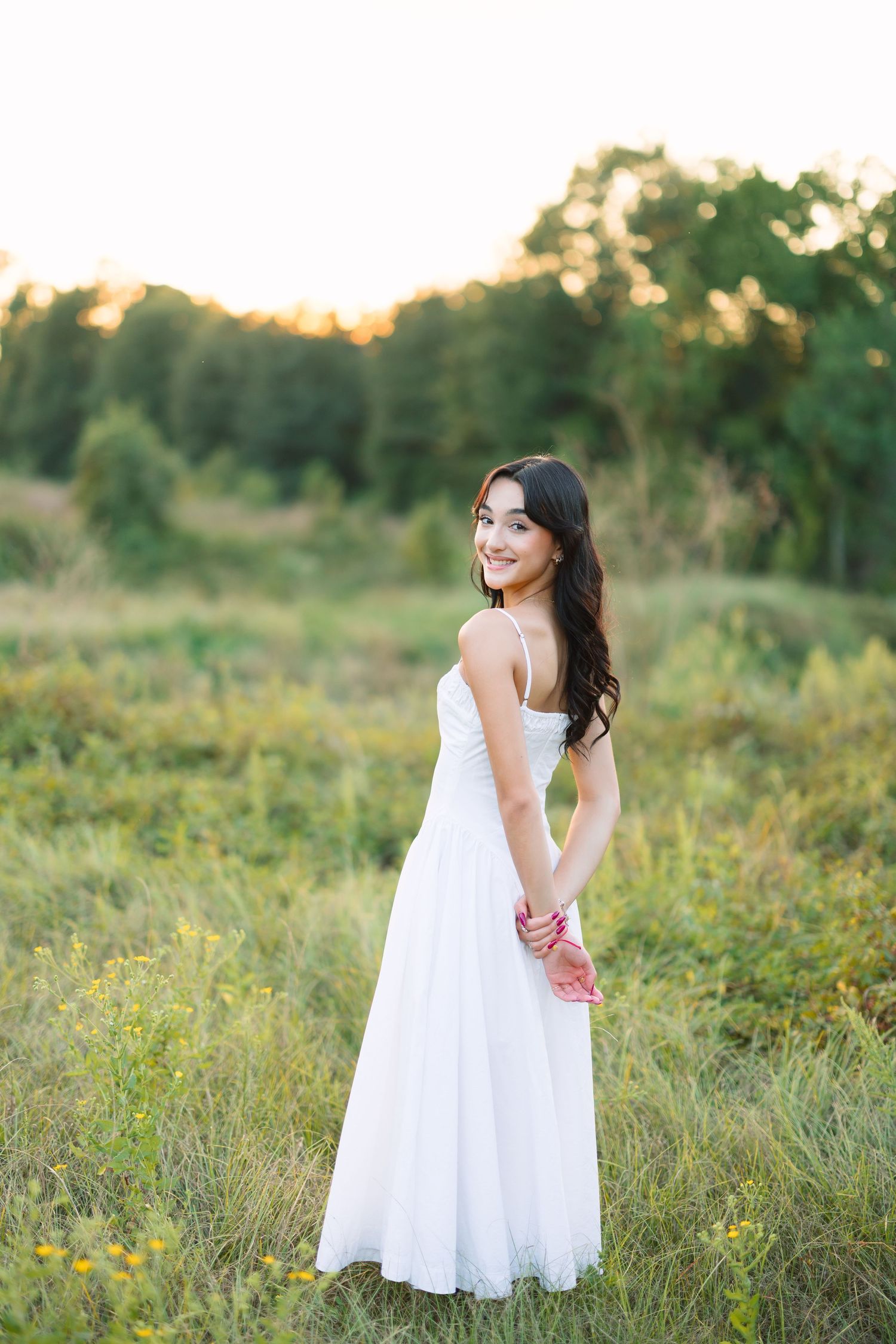 Ethereal outdoor photography in a white dress among wild meadow flowers.