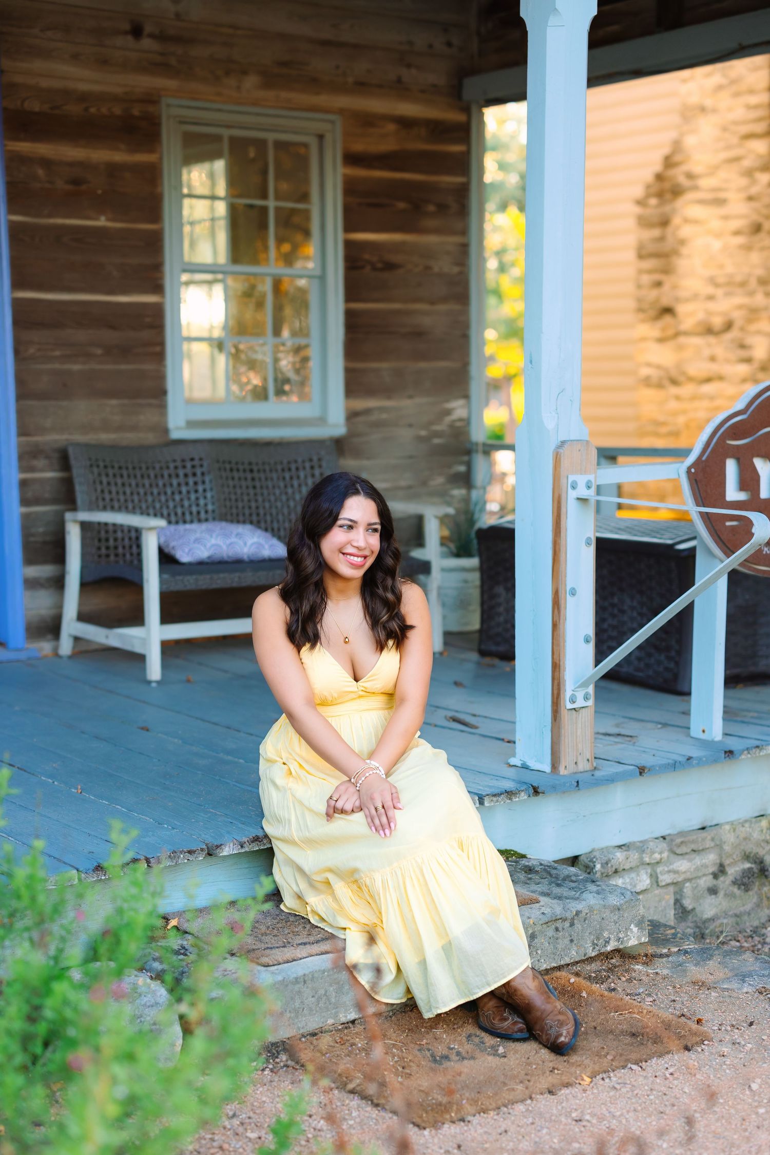 A yellow sundress is modeled on a rustic cabin porch with wooden details.