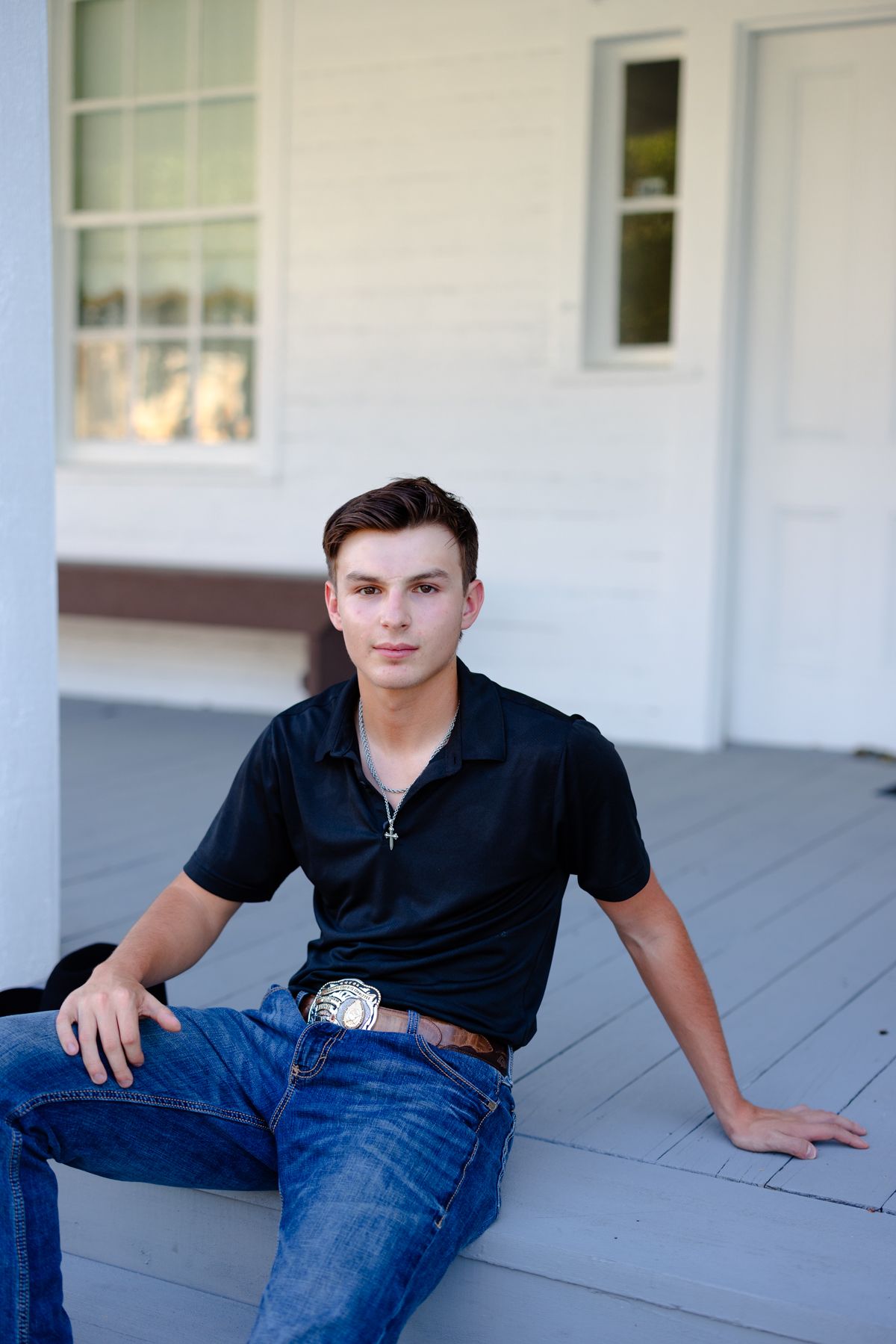 A person in a black polo shirt and blue jeans lounges casually on a white porch in three similar poses.