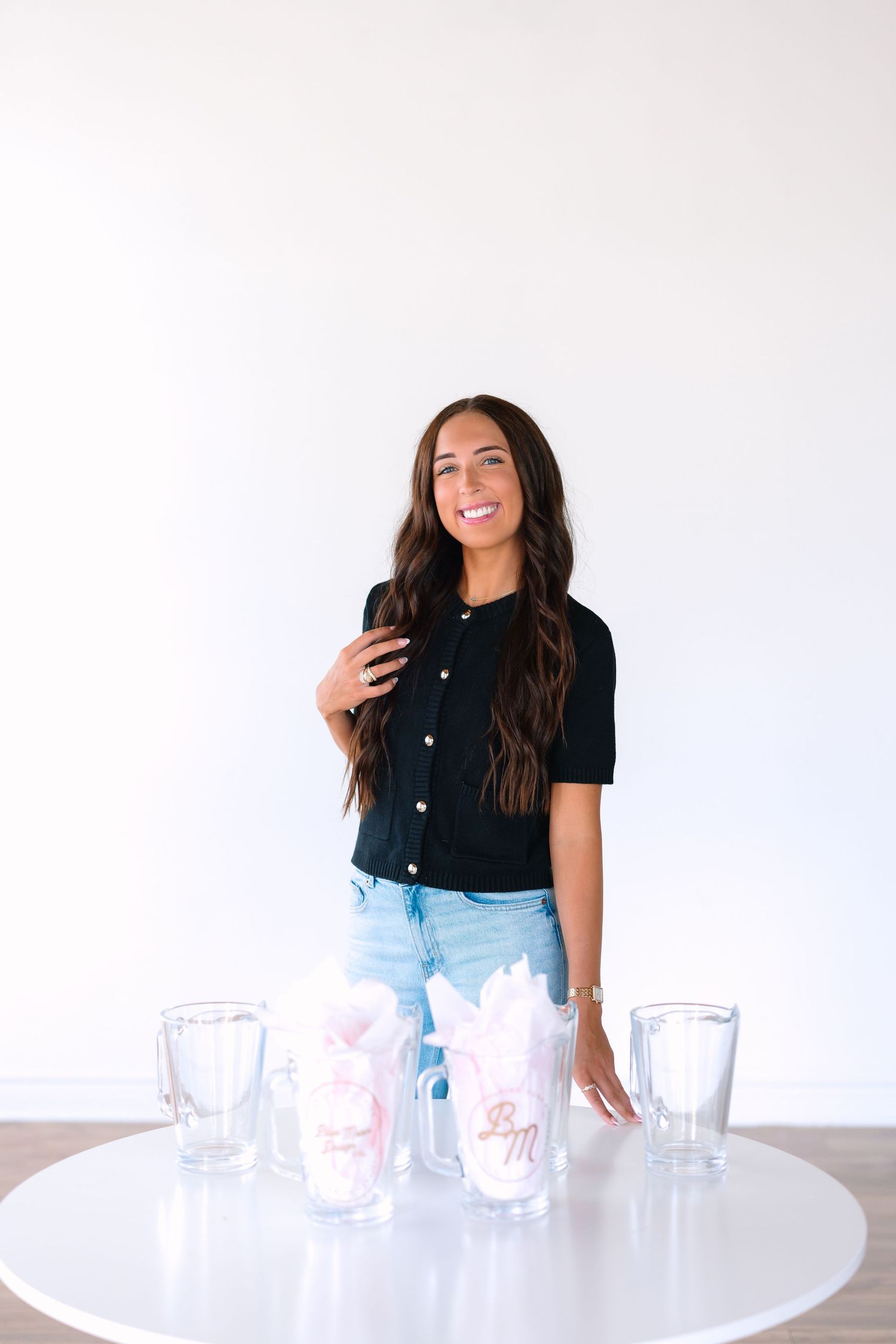 Person in casual attire posing near white table with empty glasses.