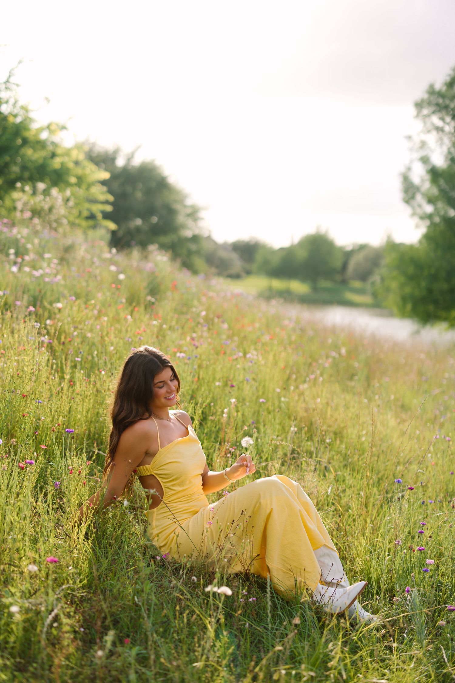 A person in a yellow sundress poses candidly in a field of wildflowers.