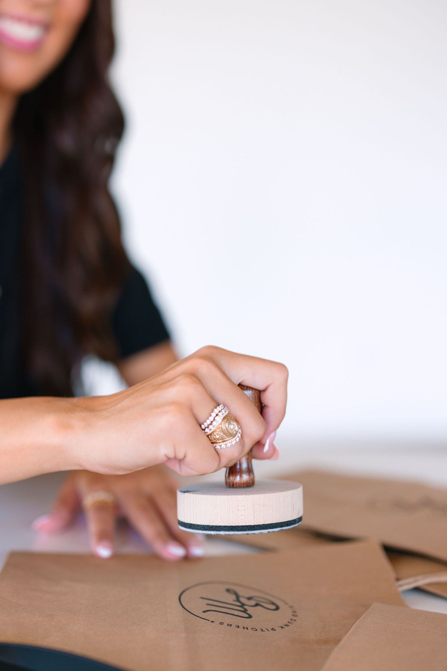Close-up shots of hands working with stamps and materials on a brown surface.