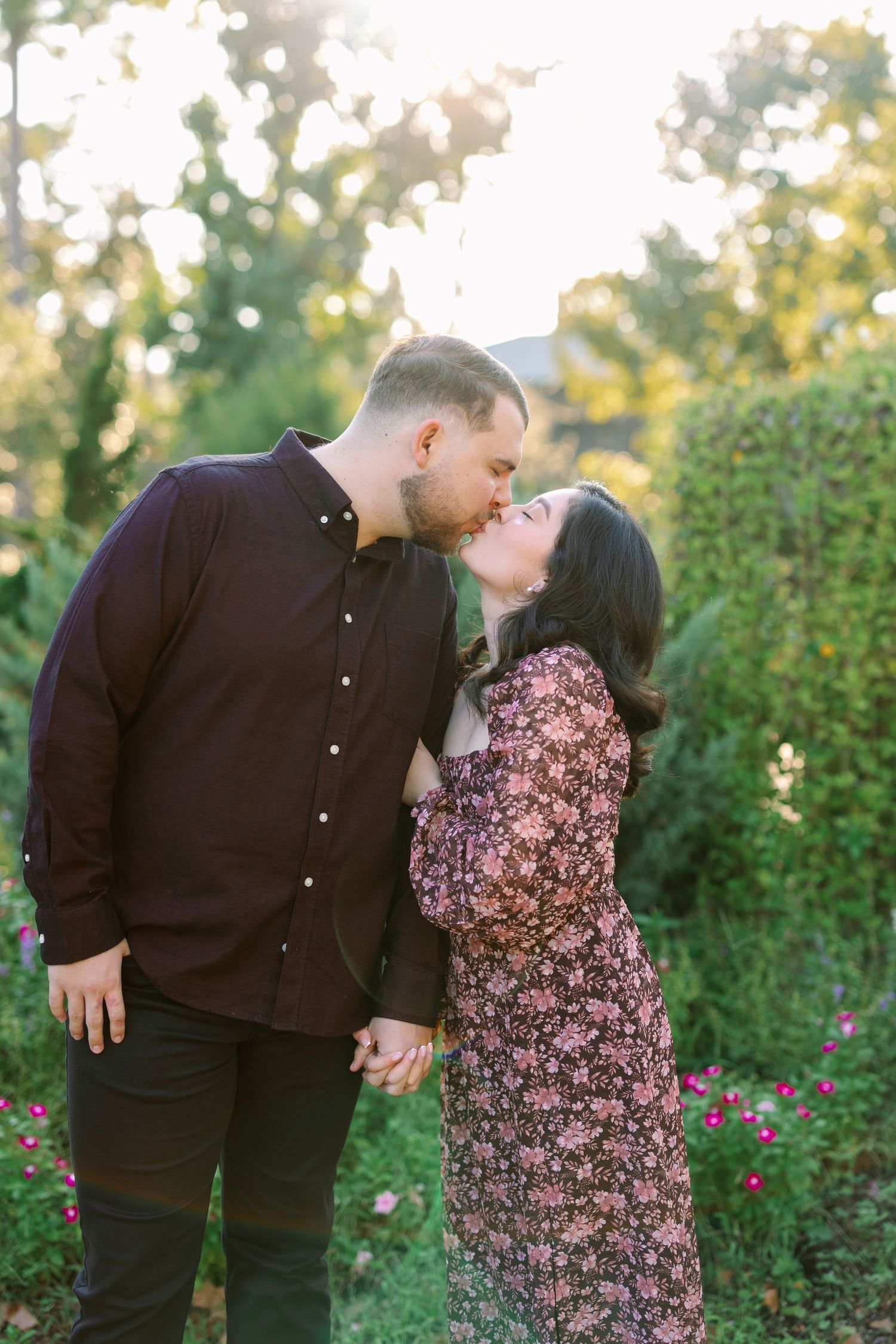 Romantic couple embracing in a garden setting during golden hour.